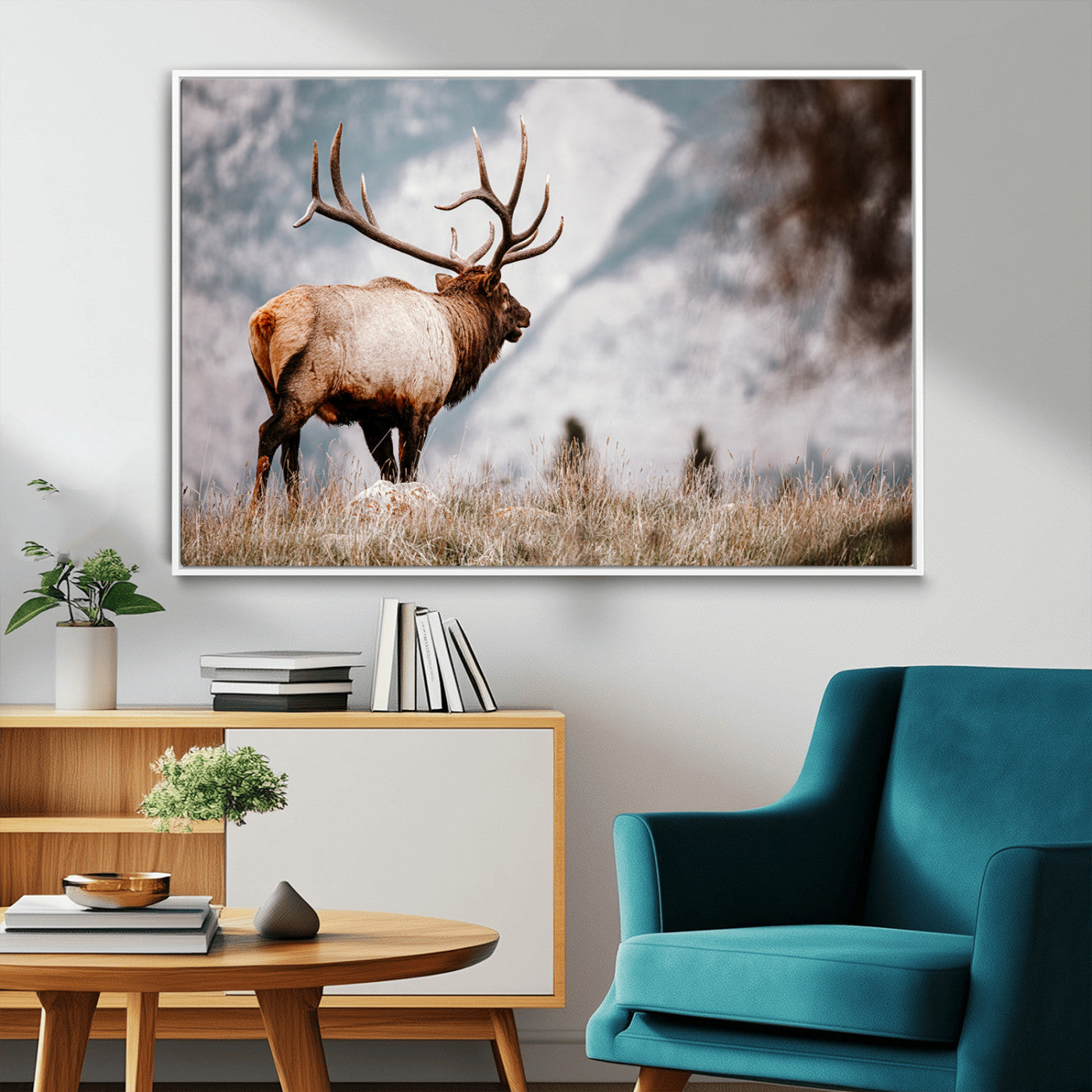 Majestic elk with large antlers standing in grass with snowy mountains in background, perfect for rustic cabin or lodge style decor.