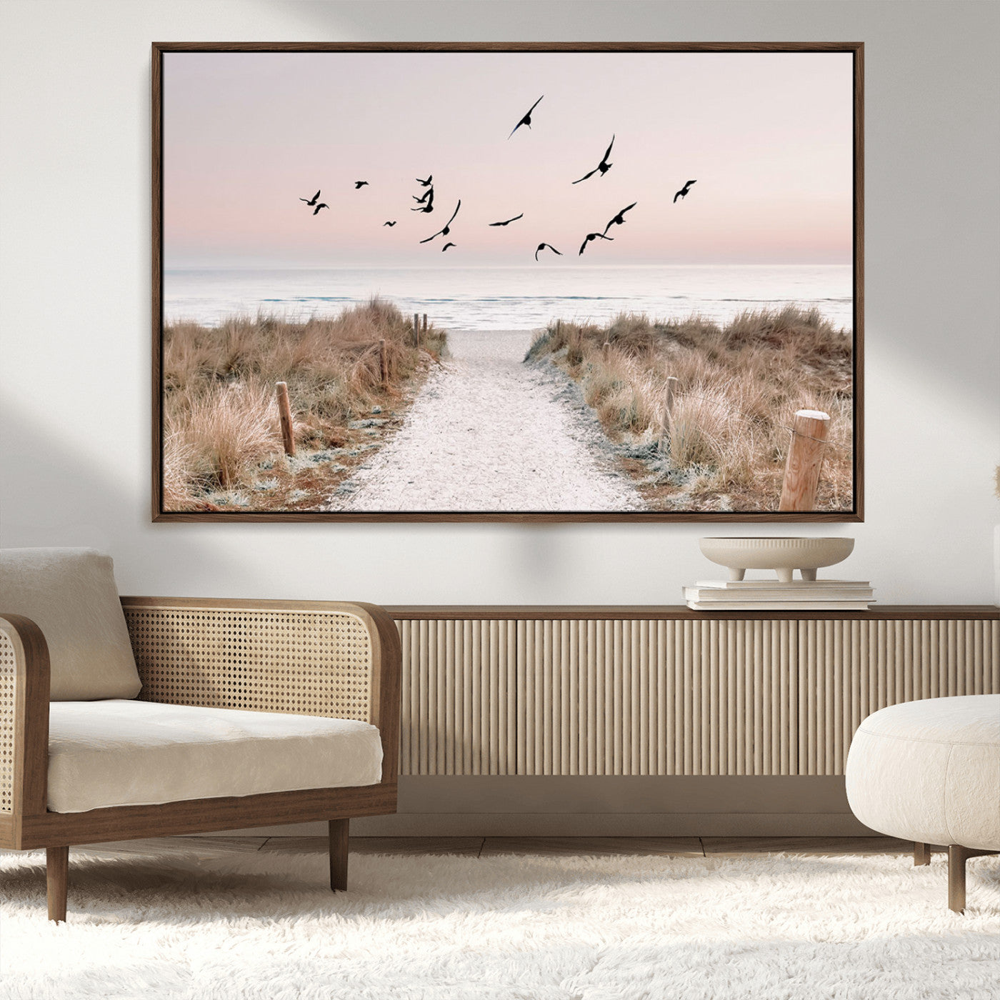 A peaceful coastal pathway leading to the ocean, with birds flying across a soft pastel sky, creating a calm and scenic beach atmosphere.