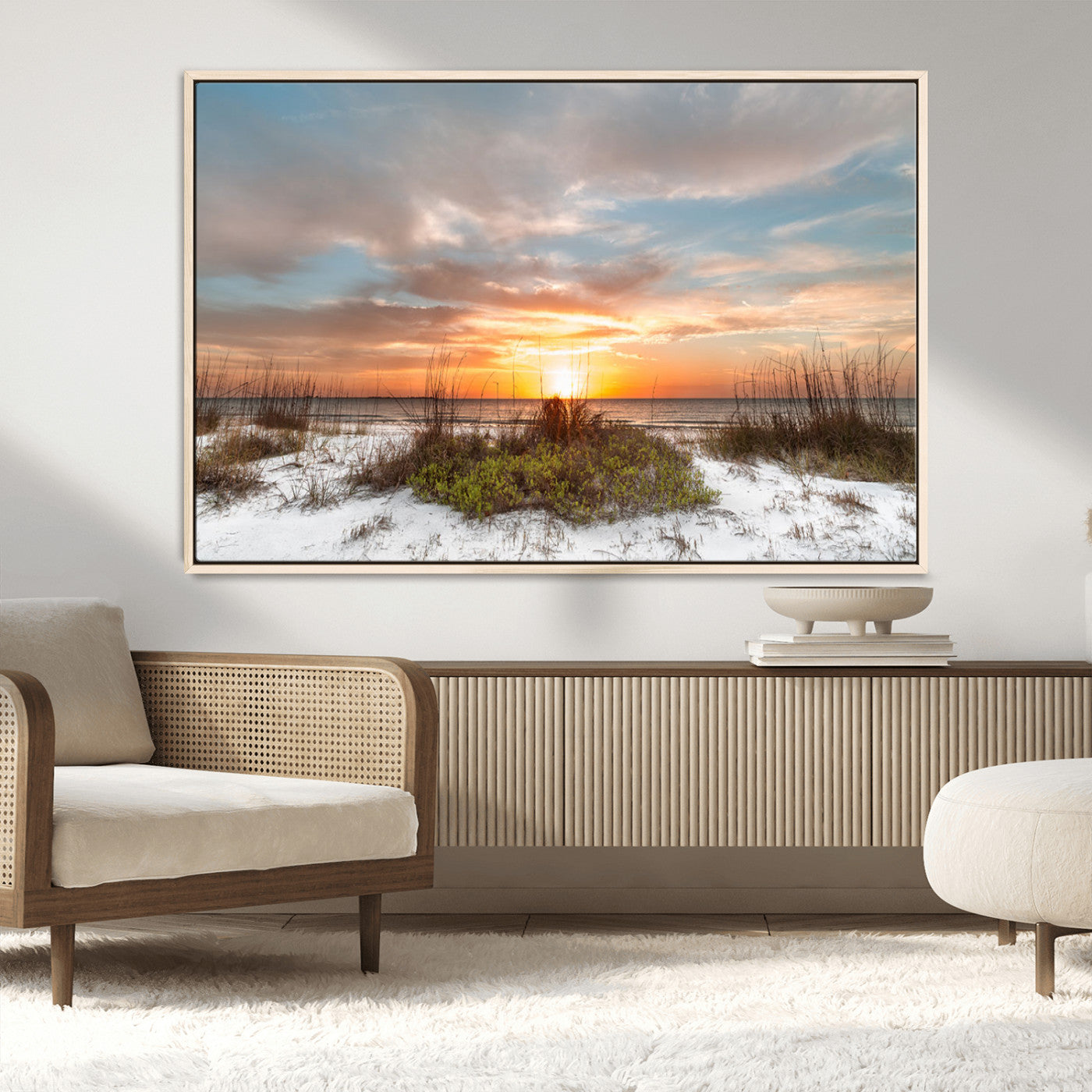 A tranquil beach scene featuring golden sunset hues over the water, with grasses in the foreground and a peaceful, serene atmosphere.