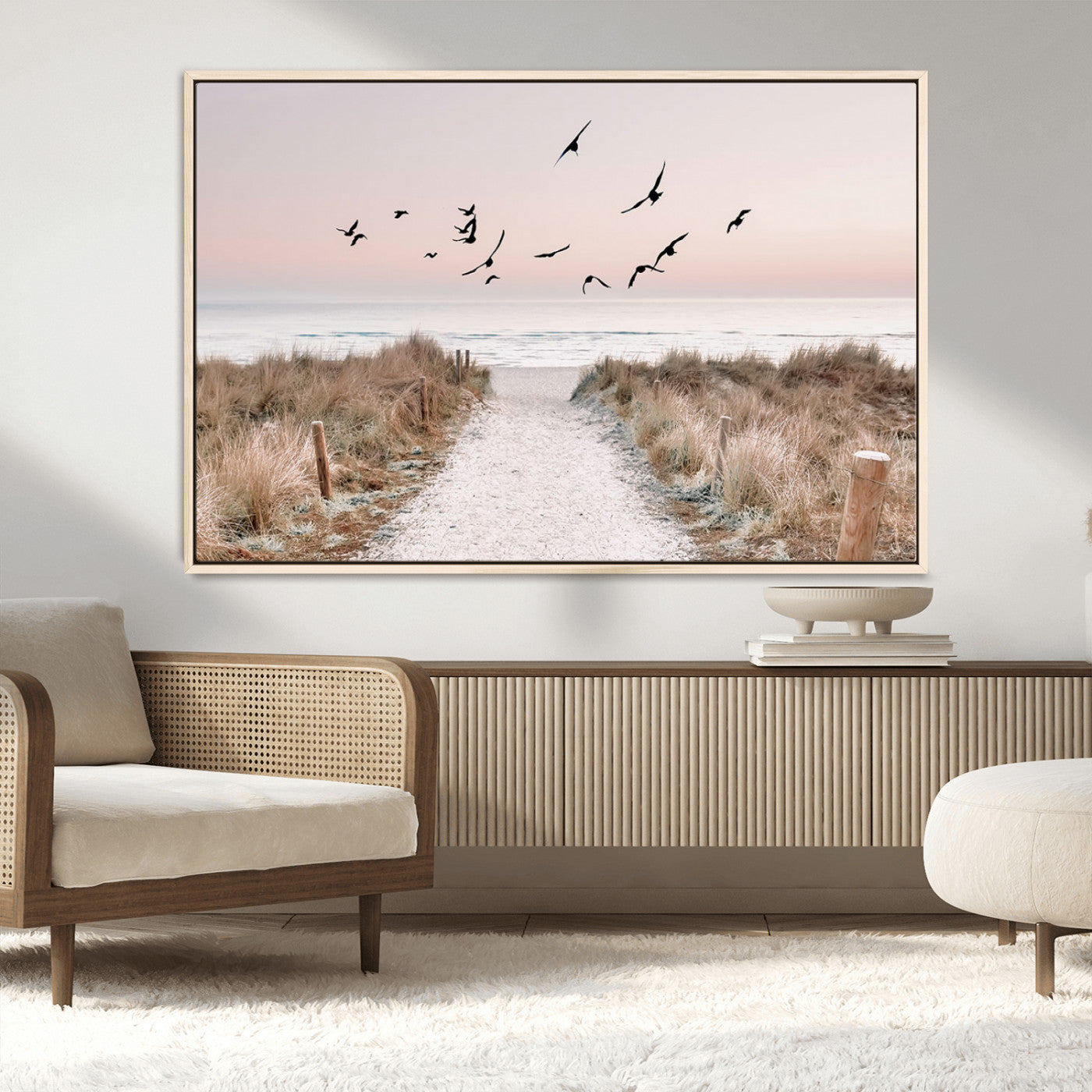 A peaceful coastal pathway leading to the ocean, with birds flying across a soft pastel sky, creating a calm and scenic beach atmosphere.