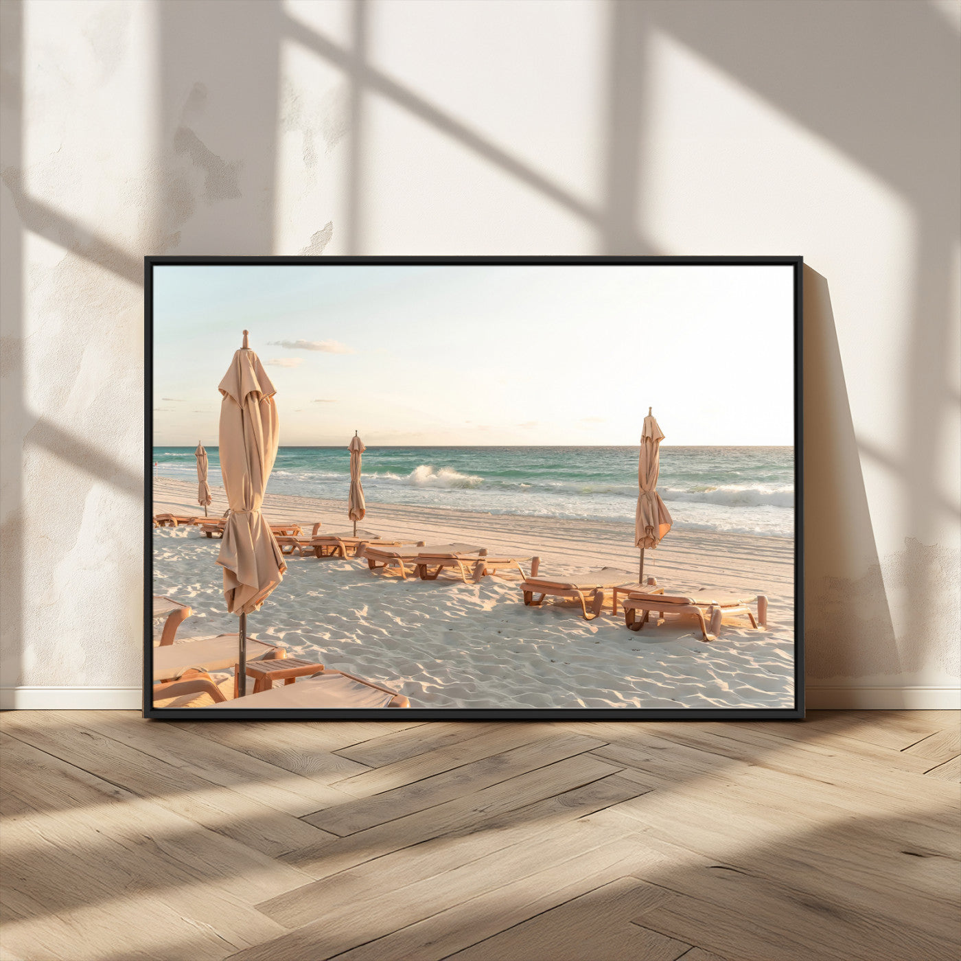 Minimalist photo of empty beach loungers and umbrellas on soft sand, ideal for calm seaside or pastel coastal-style home decor.