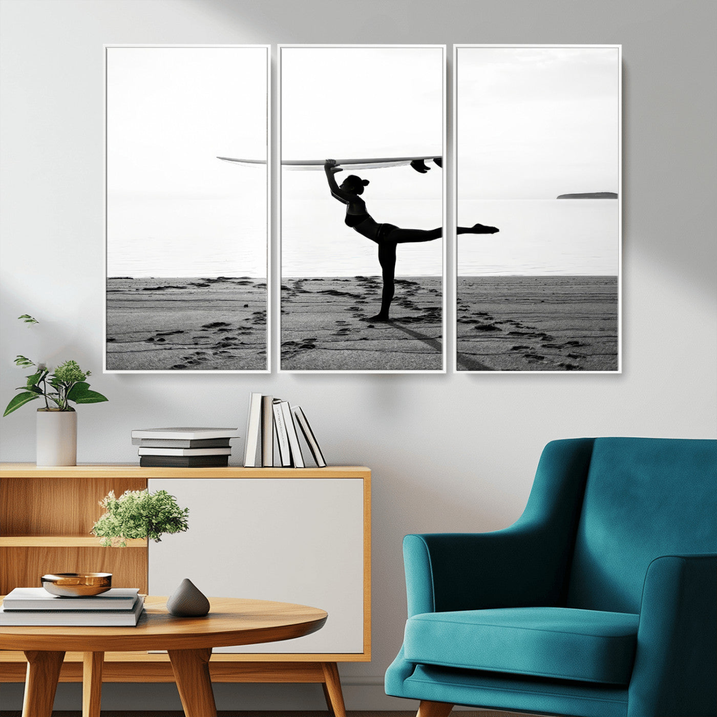 A woman balances a surfboard on her head while striking a yoga pose on the beach, silhouetted against a calm ocean horizon.