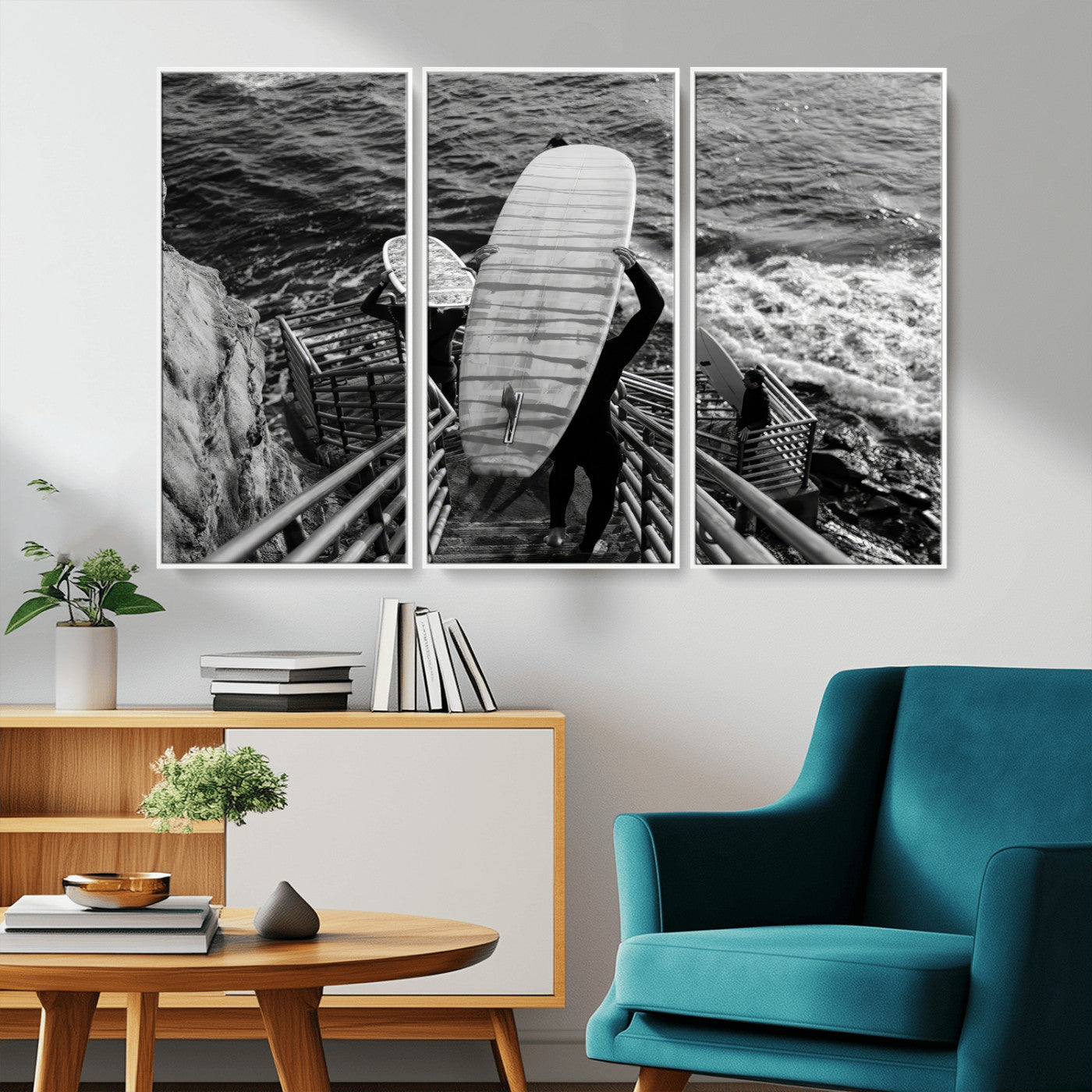 Black and white photo of surfers carrying boards down a rugged cliffside stairway, capturing a bold and adventurous coastal scene.