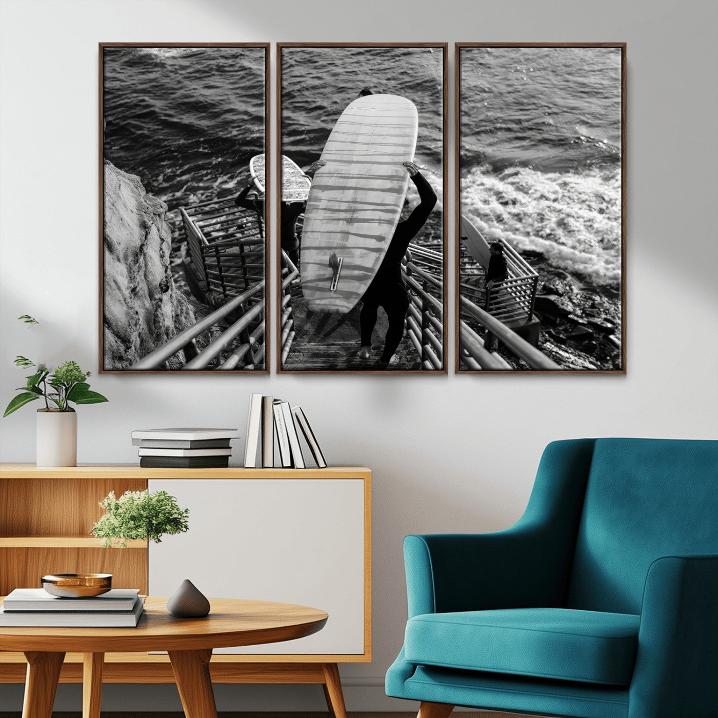 Black and white photo of surfers carrying boards down a rugged cliffside stairway, capturing a bold and adventurous coastal scene.