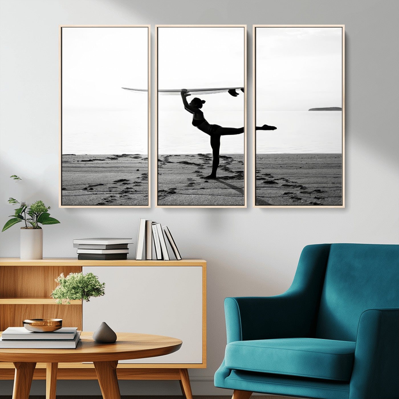 A woman balances a surfboard on her head while striking a yoga pose on the beach, silhouetted against a calm ocean horizon.