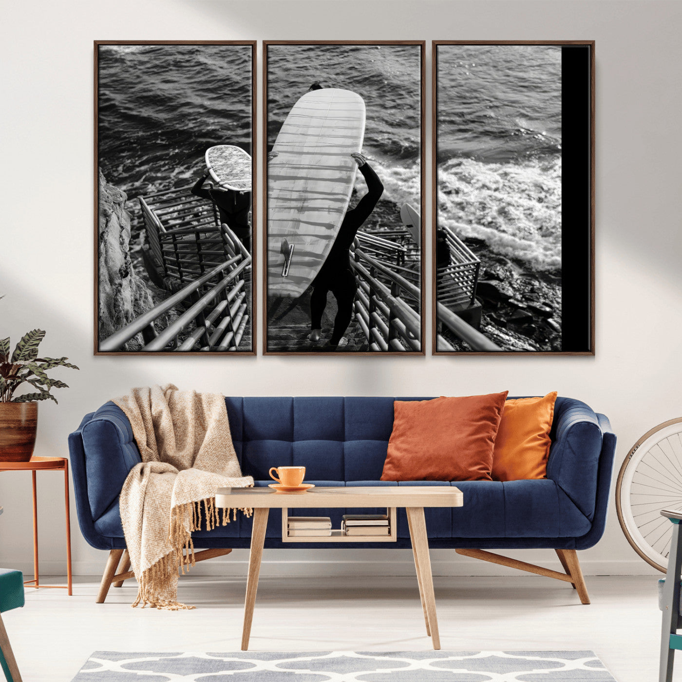 Black and white photo of surfers carrying boards down a rugged cliffside stairway, capturing a bold and adventurous coastal scene.