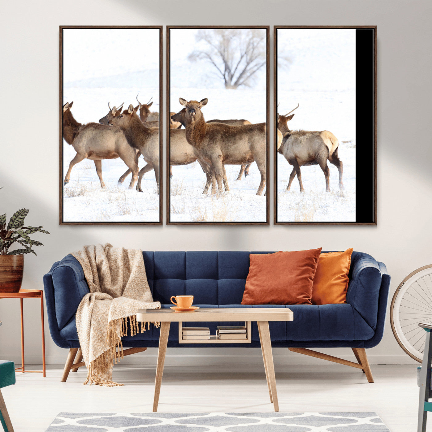 A group of elk standing on snowy terrain with a tree in the background, perfect for rustic or lodge-style winter wall decor.
