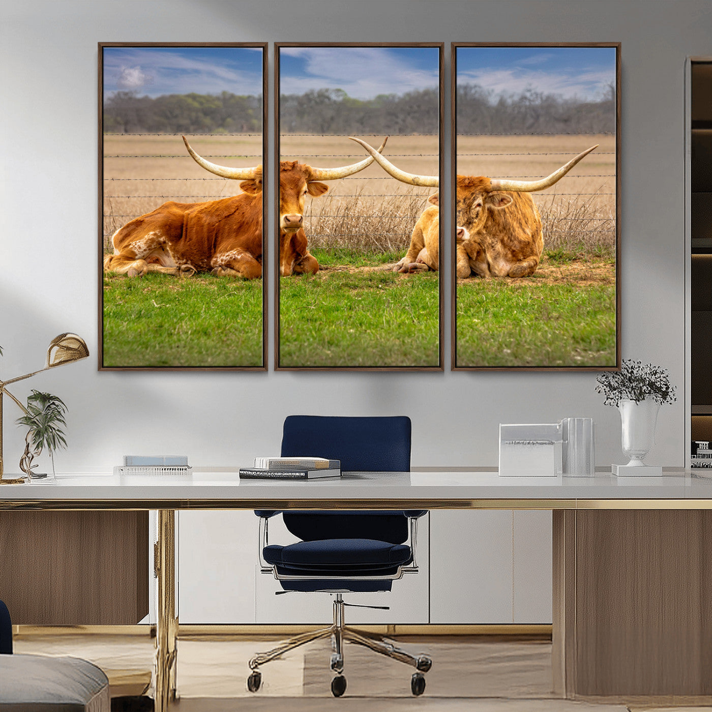 Two longhorn cows lying on green grass in front of a golden field and trees under a blue sky, perfect for rustic country wall decor.