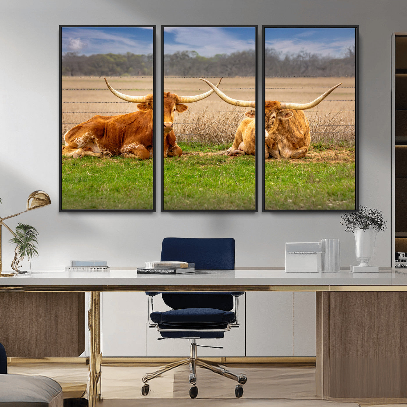 Two longhorn cows lying on green grass in front of a golden field and trees under a blue sky, perfect for rustic country wall decor.
