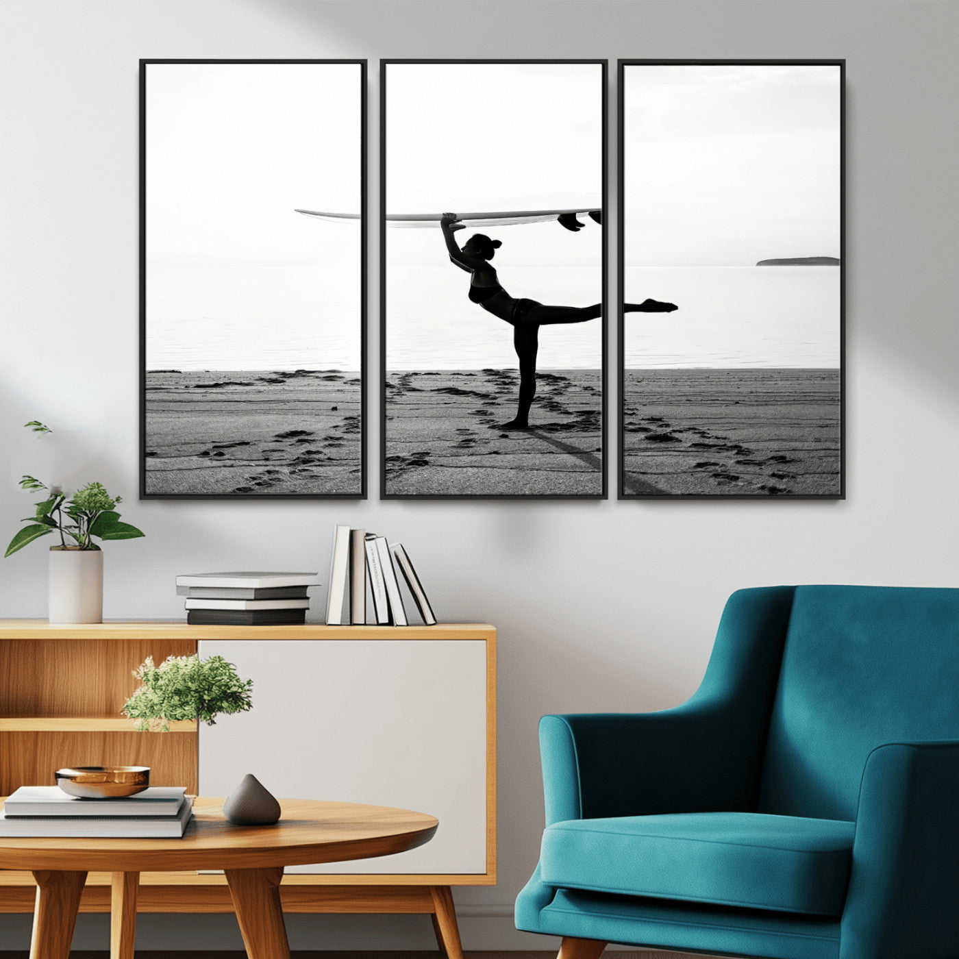 A woman balances a surfboard on her head while striking a yoga pose on the beach, silhouetted against a calm ocean horizon.