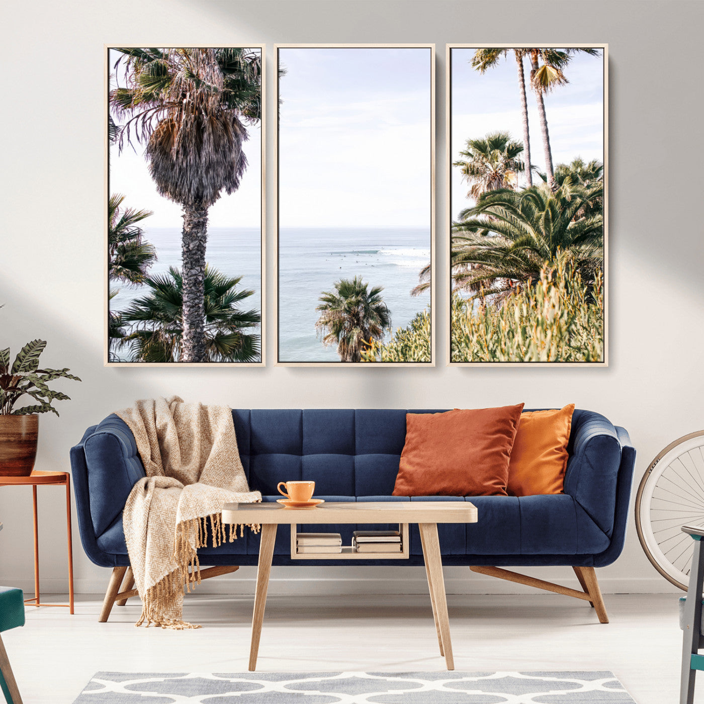 Scenic coastal view with tall palm trees overlooking a calm ocean, soft blue waves, and surfers in the distance, creating a peaceful tropical vibe.