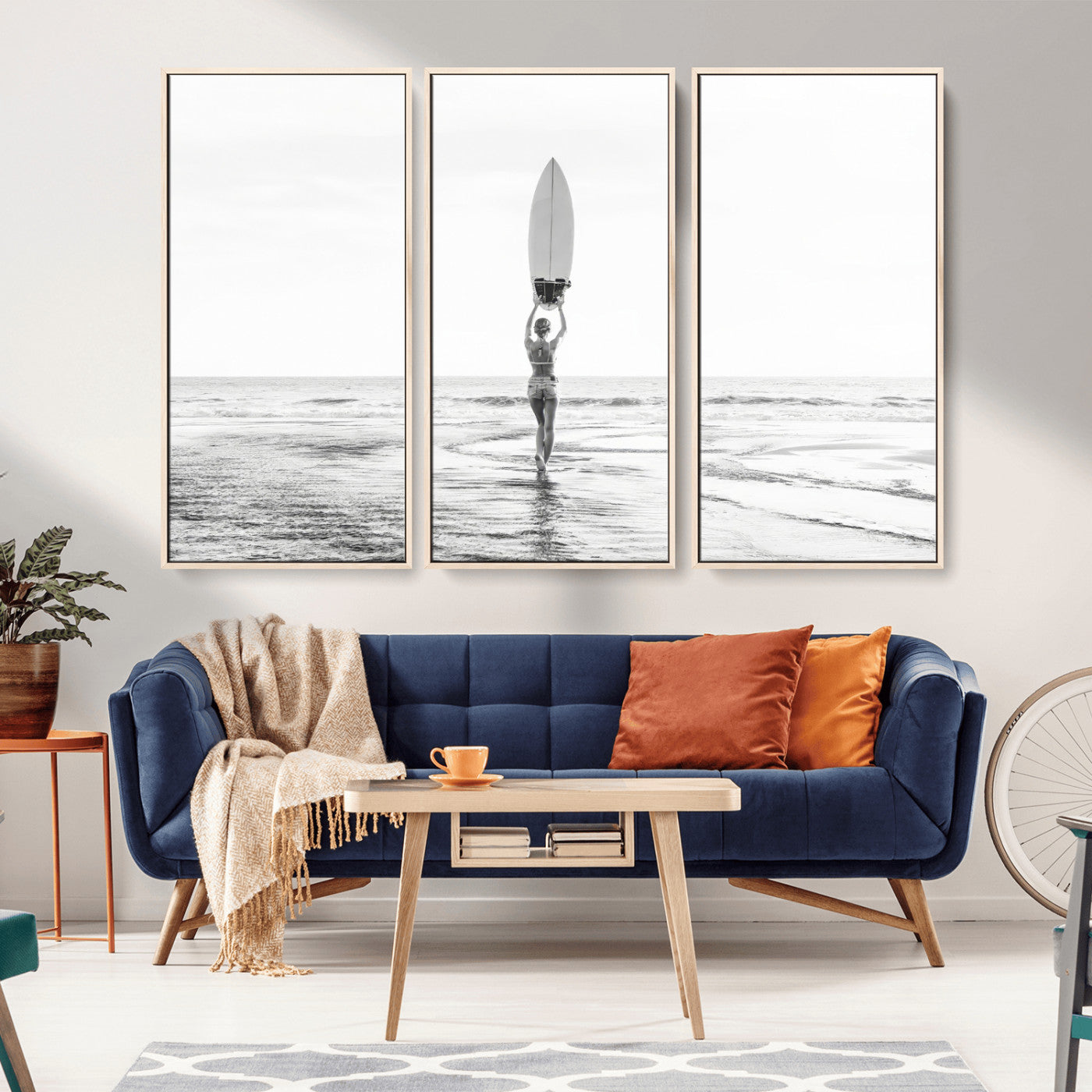 Black and white image of a female surfer holding a surfboard above her head while walking toward the ocean, creating a minimalist and bold coastal aesthetic.