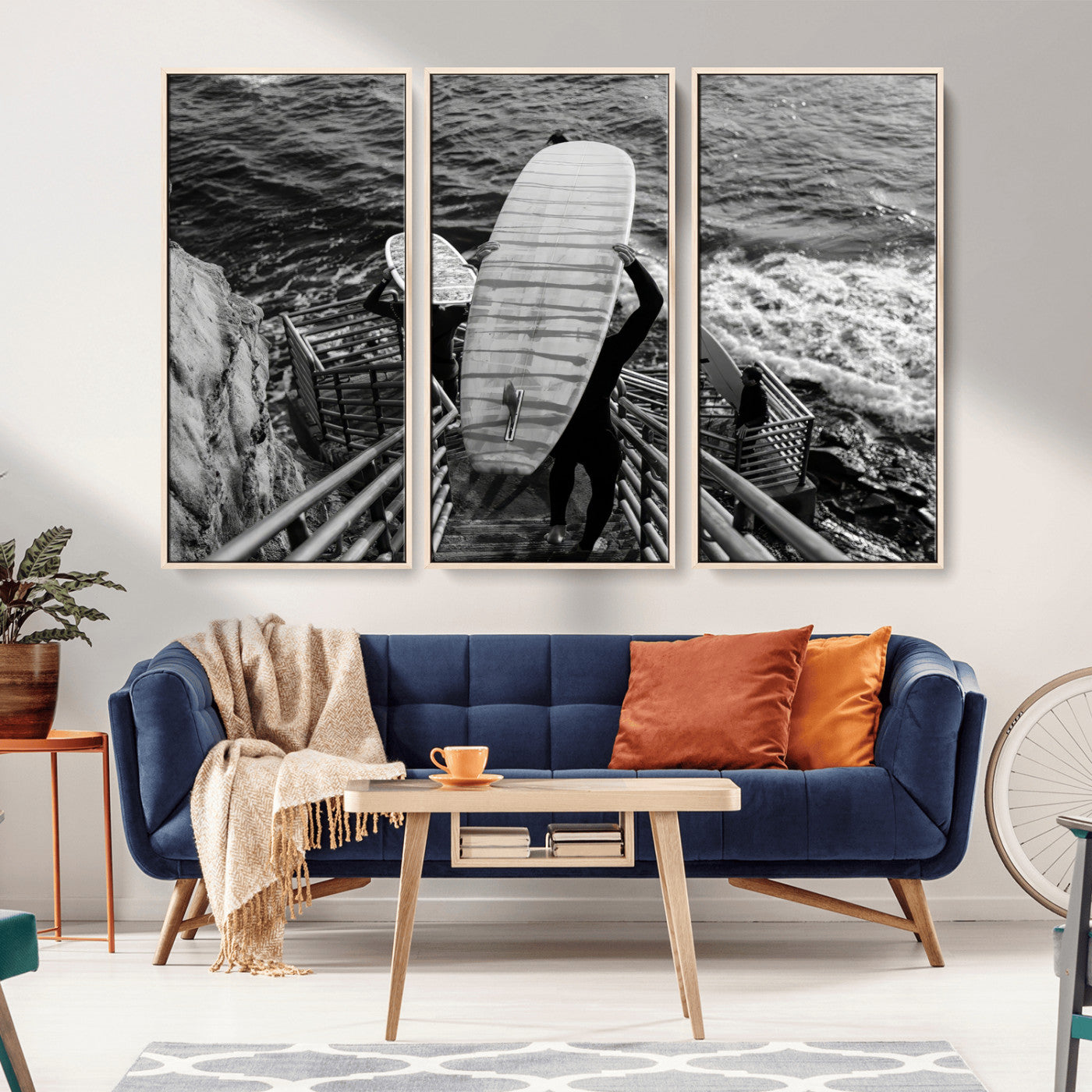 Black and white photo of surfers carrying boards down a rugged cliffside stairway, capturing a bold and adventurous coastal scene.