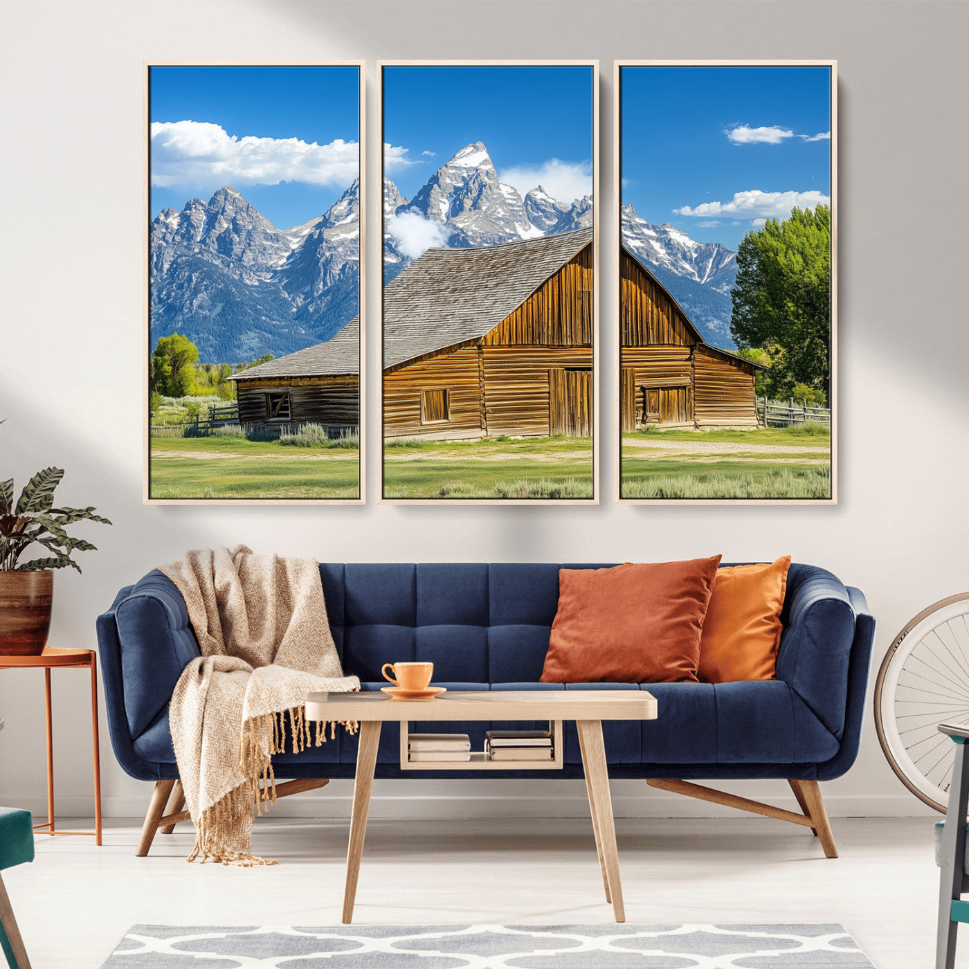 A rustic wooden barn sits in front of towering mountain peaks under a clear blue sky, perfect for farmhouse or cabin style interiors.