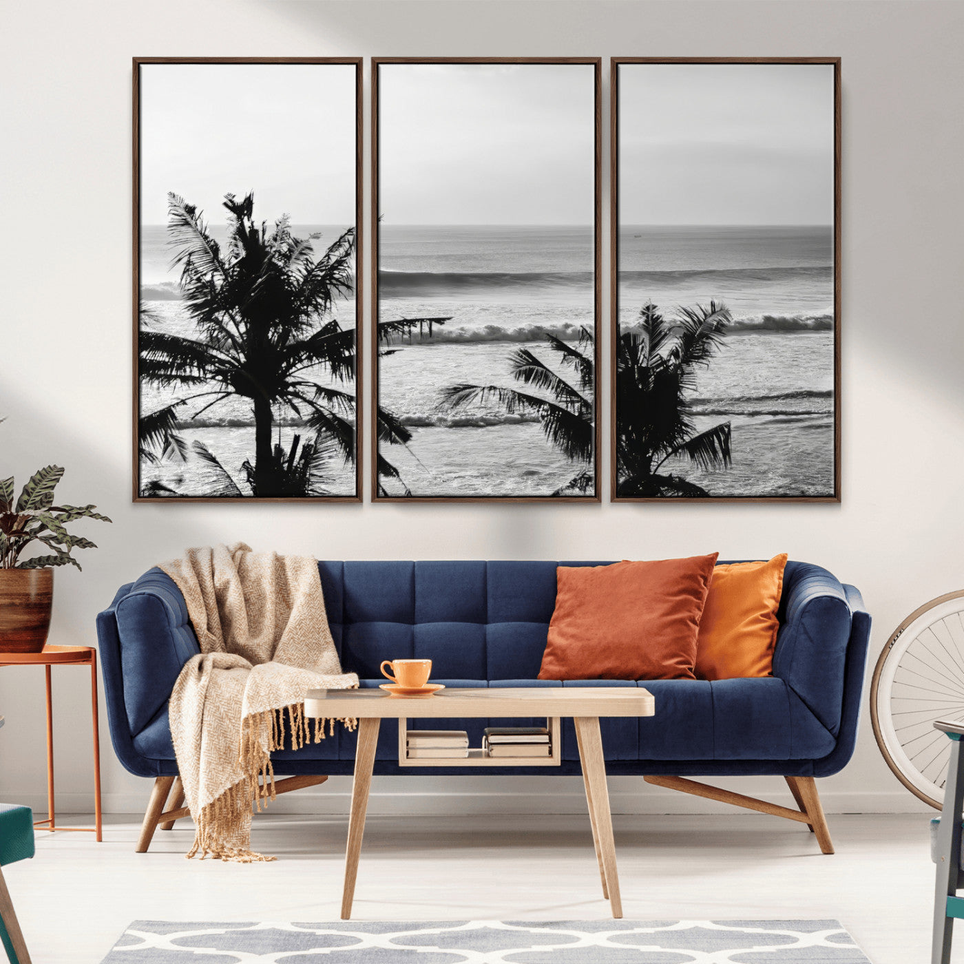 Black and white view of ocean waves crashing on a tropical coastline, framed by silhouetted palm trees under a vast, open sky.