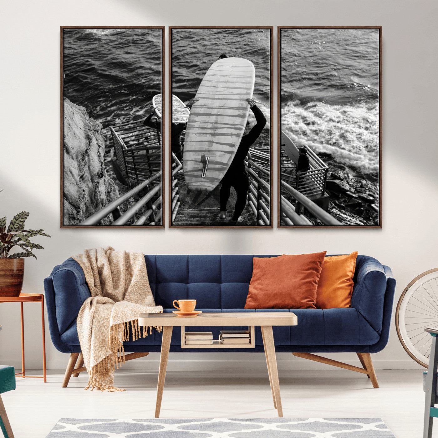 Black and white photo of surfers carrying boards down a rugged cliffside stairway, capturing a bold and adventurous coastal scene.