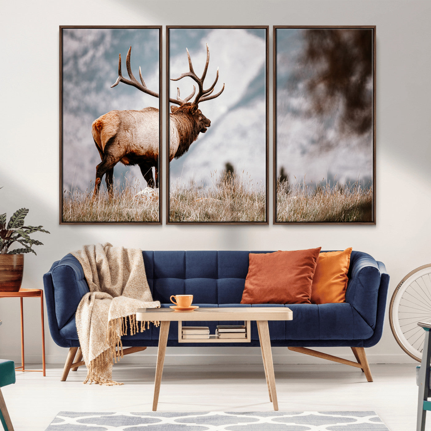 Majestic elk with large antlers standing in grass with snowy mountains in background, perfect for rustic cabin or lodge style decor.