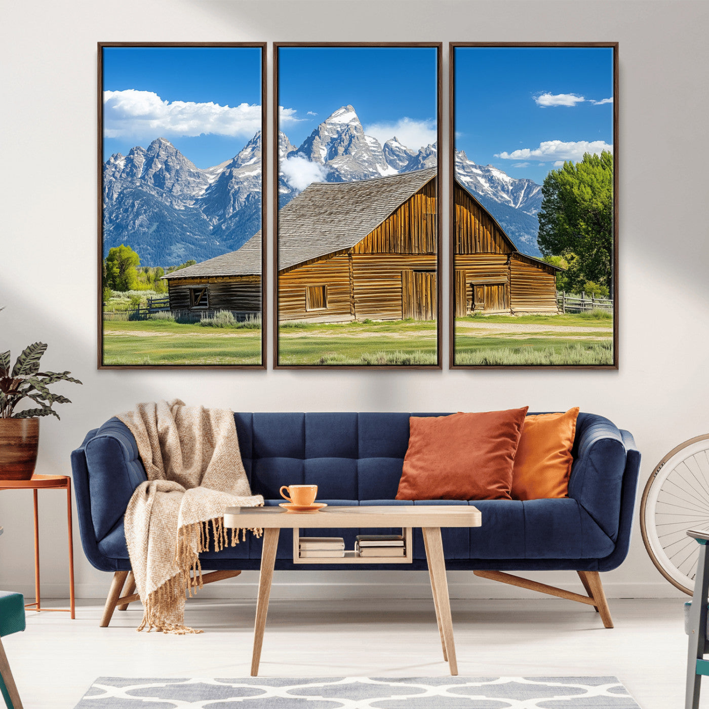 A rustic wooden barn sits in front of towering mountain peaks under a clear blue sky, perfect for farmhouse or cabin style interiors.