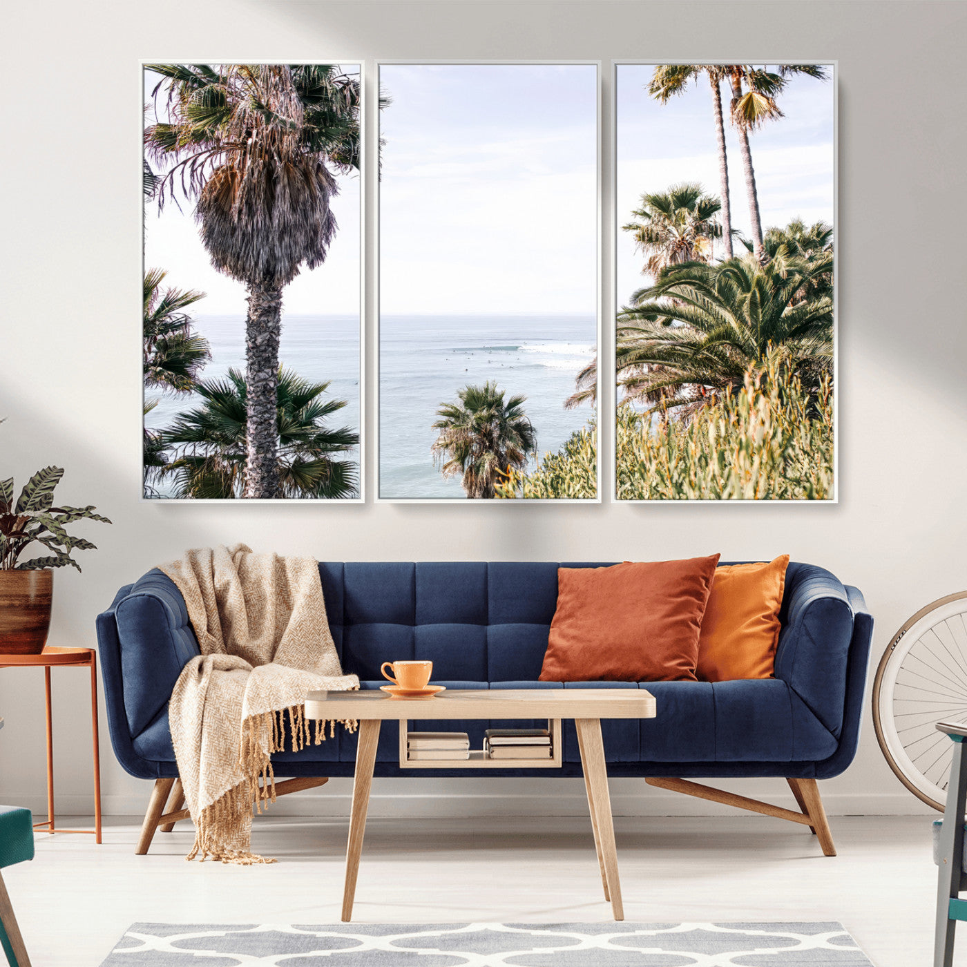 Scenic coastal view with tall palm trees overlooking a calm ocean, soft blue waves, and surfers in the distance, creating a peaceful tropical vibe.