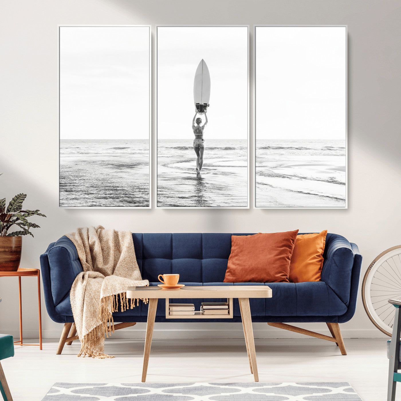 Black and white image of a female surfer holding a surfboard above her head while walking toward the ocean, creating a minimalist and bold coastal aesthetic.