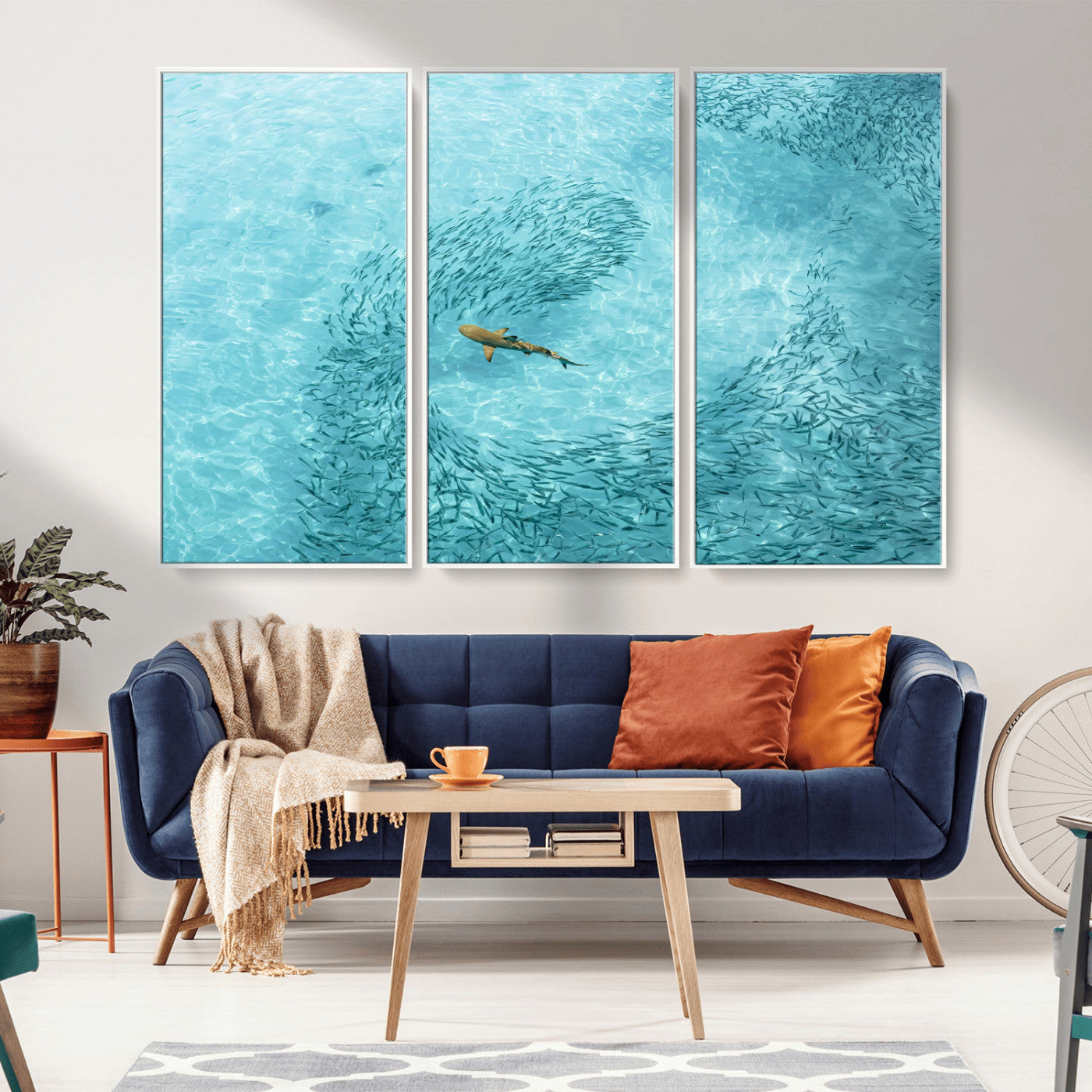 Aerial view of a shark swimming through a swirl of fish in clear turquoise waters, perfect for calm coastal or beach house decor.