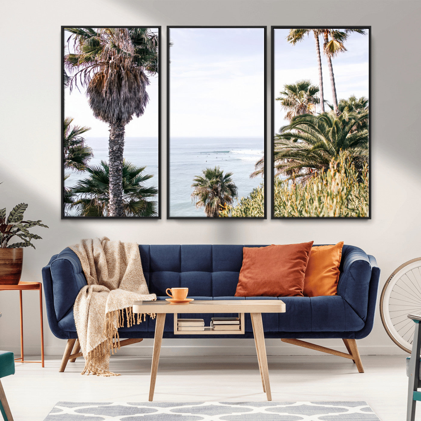 Scenic coastal view with tall palm trees overlooking a calm ocean, soft blue waves, and surfers in the distance, creating a peaceful tropical vibe.