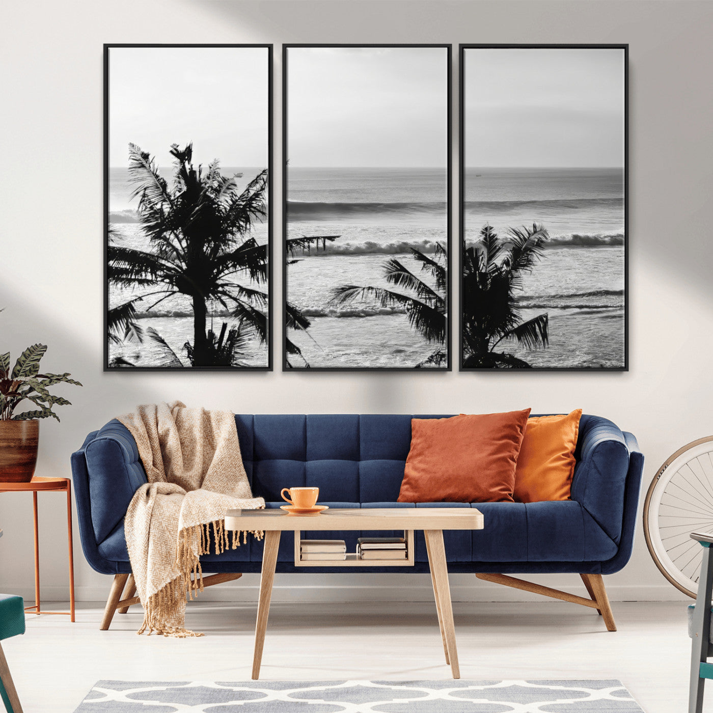 Black and white view of ocean waves crashing on a tropical coastline, framed by silhouetted palm trees under a vast, open sky.