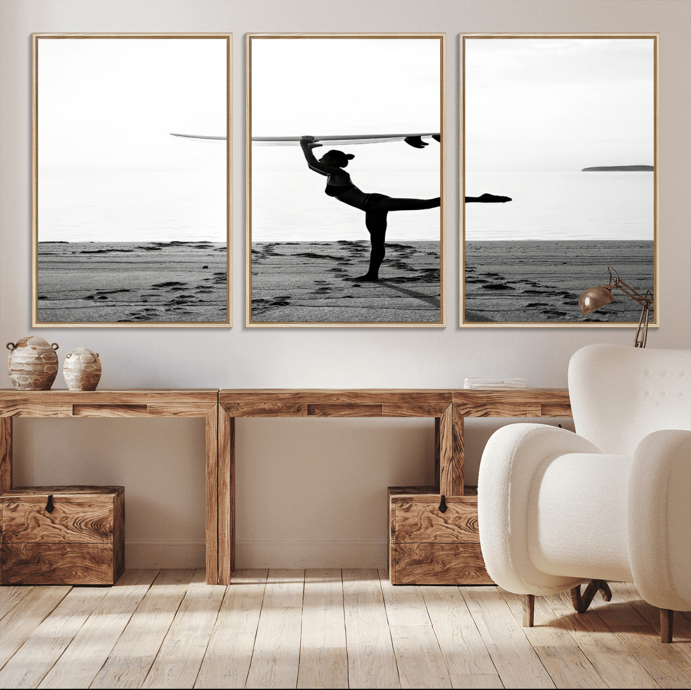 A woman balances a surfboard on her head while striking a yoga pose on the beach, silhouetted against a calm ocean horizon.