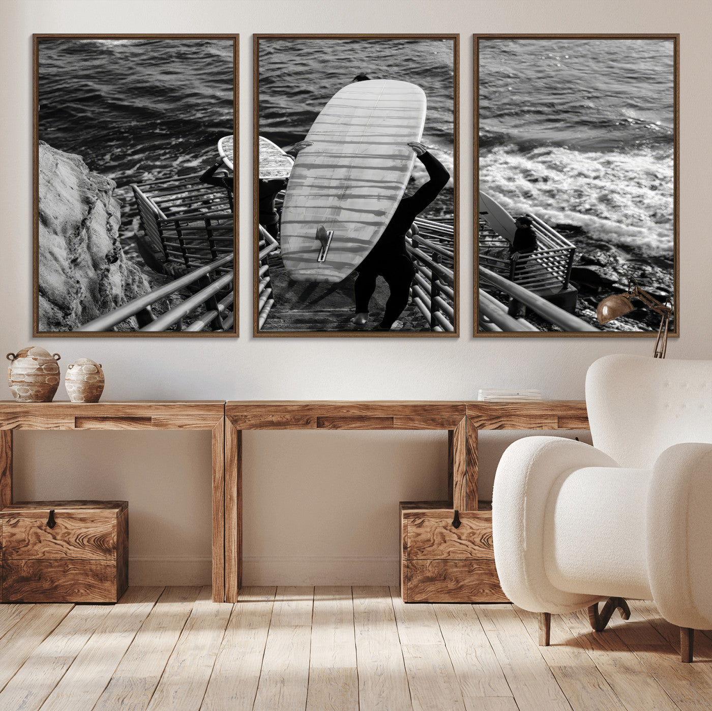 Black and white photo of surfers carrying boards down a rugged cliffside stairway, capturing a bold and adventurous coastal scene.