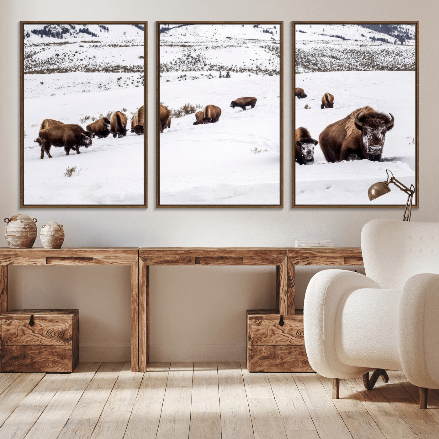 A herd of bison walking through deep snow in a mountain valley, perfect for rustic, cabin or western-themed wall decor.