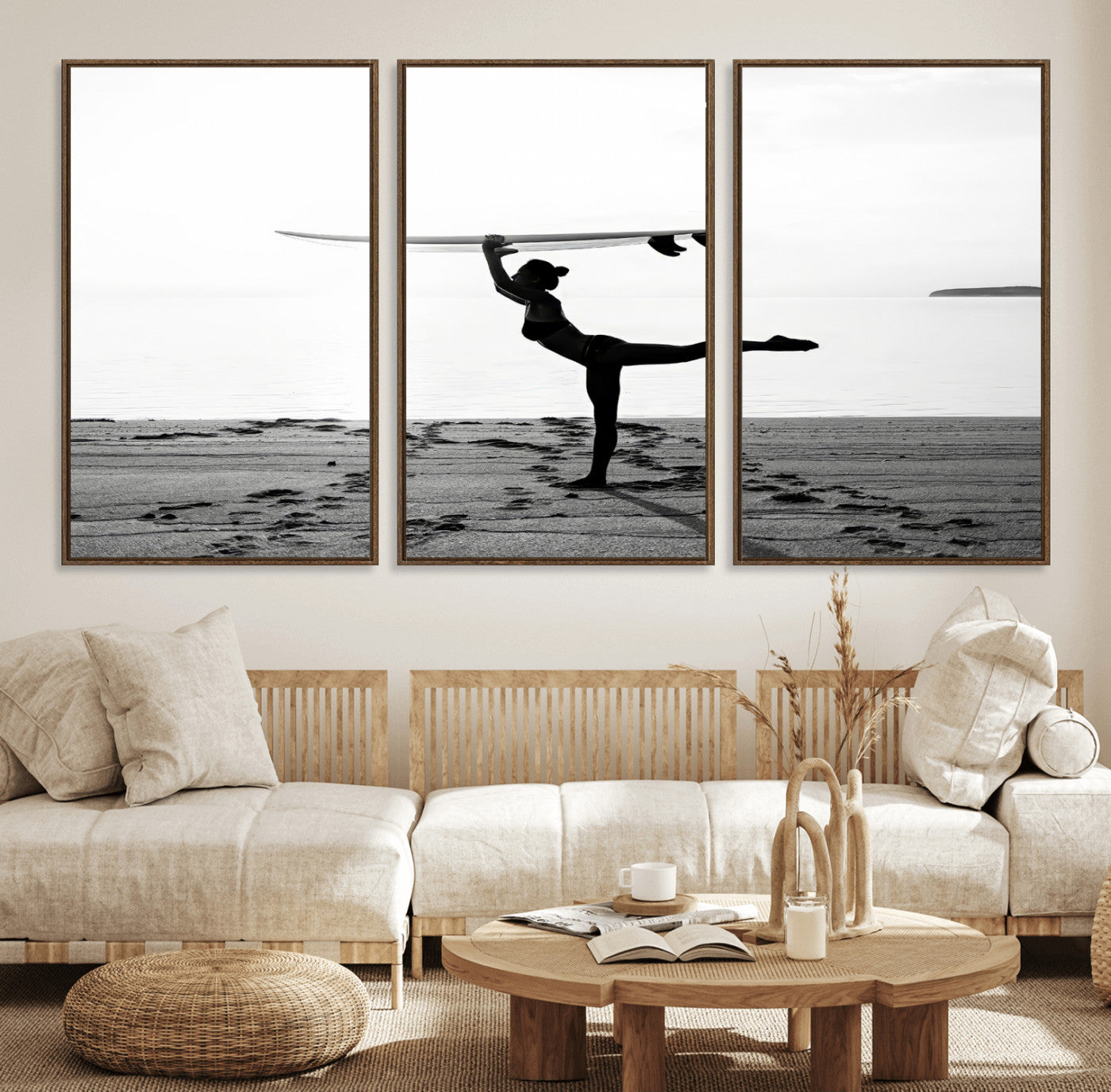 A woman balances a surfboard on her head while striking a yoga pose on the beach, silhouetted against a calm ocean horizon.
