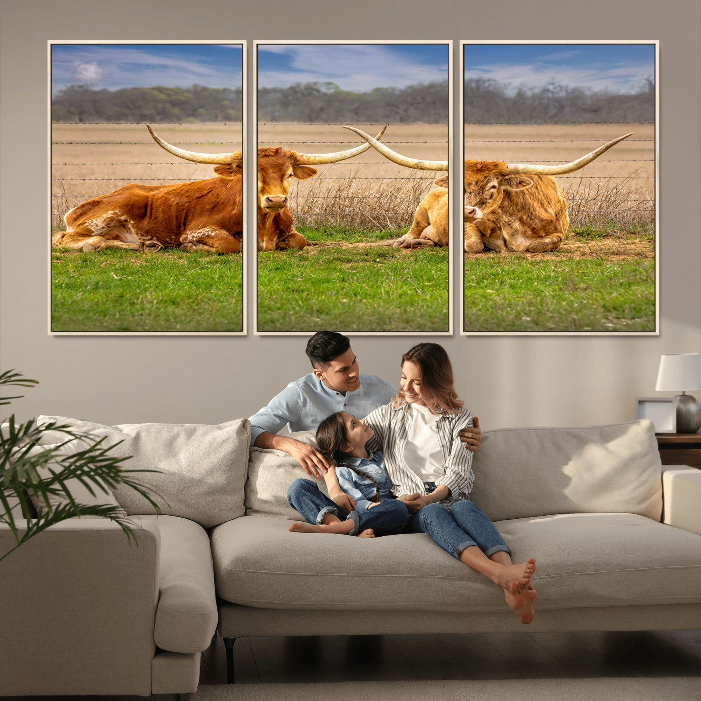 Two longhorn cows lying on green grass in front of a golden field and trees under a blue sky, perfect for rustic country wall decor.