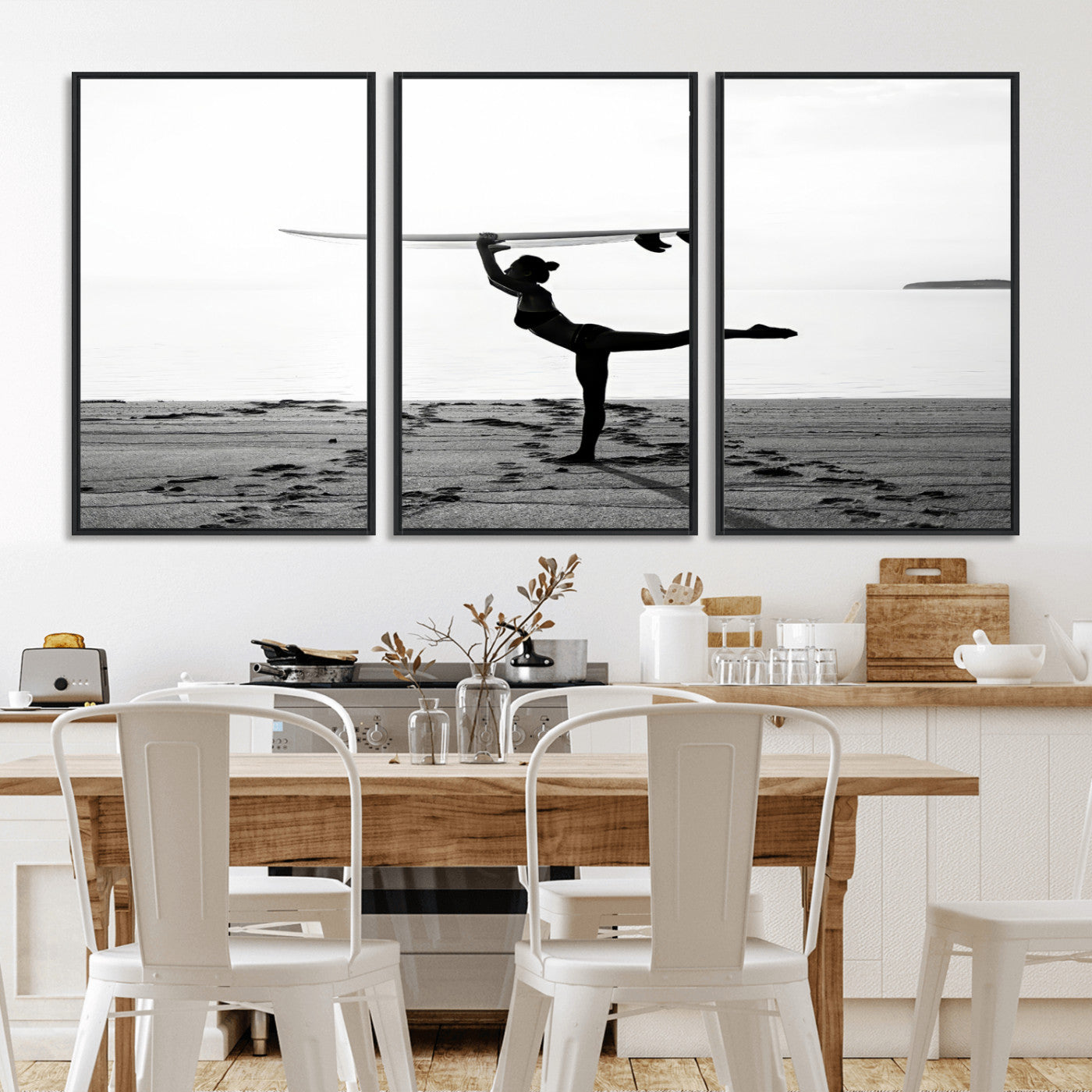 A woman balances a surfboard on her head while striking a yoga pose on the beach, silhouetted against a calm ocean horizon.