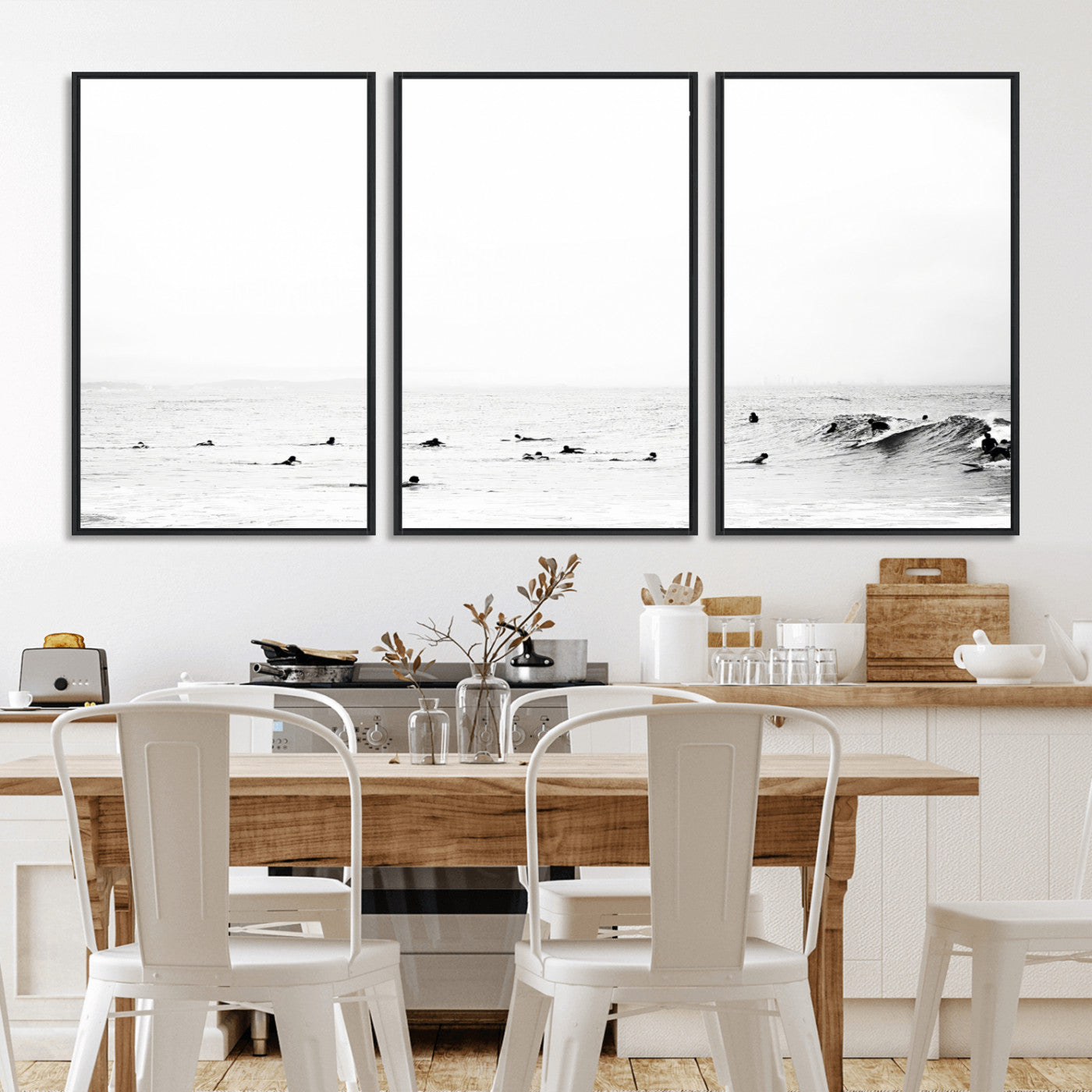 A group of surfers floating in the ocean, waiting for waves under a vast, moody sky, captured in black and white.
