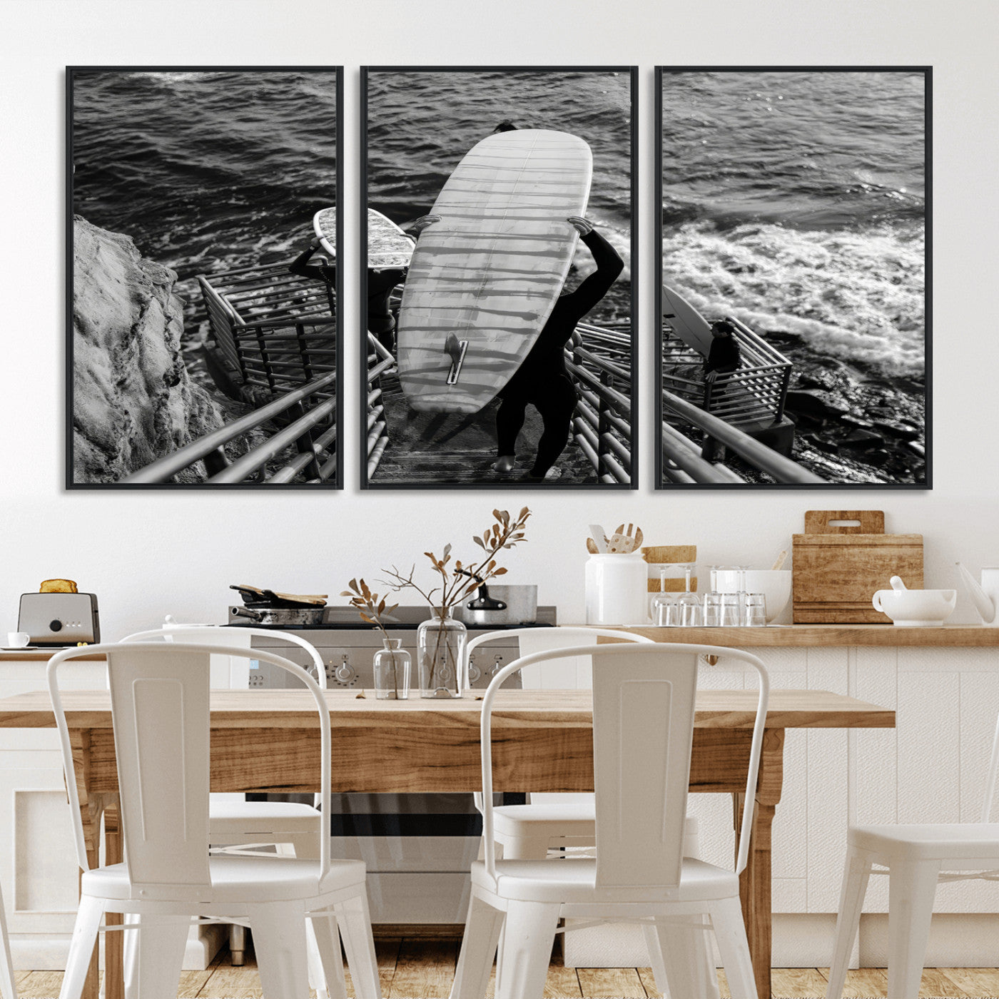Black and white photo of surfers carrying boards down a rugged cliffside stairway, capturing a bold and adventurous coastal scene.