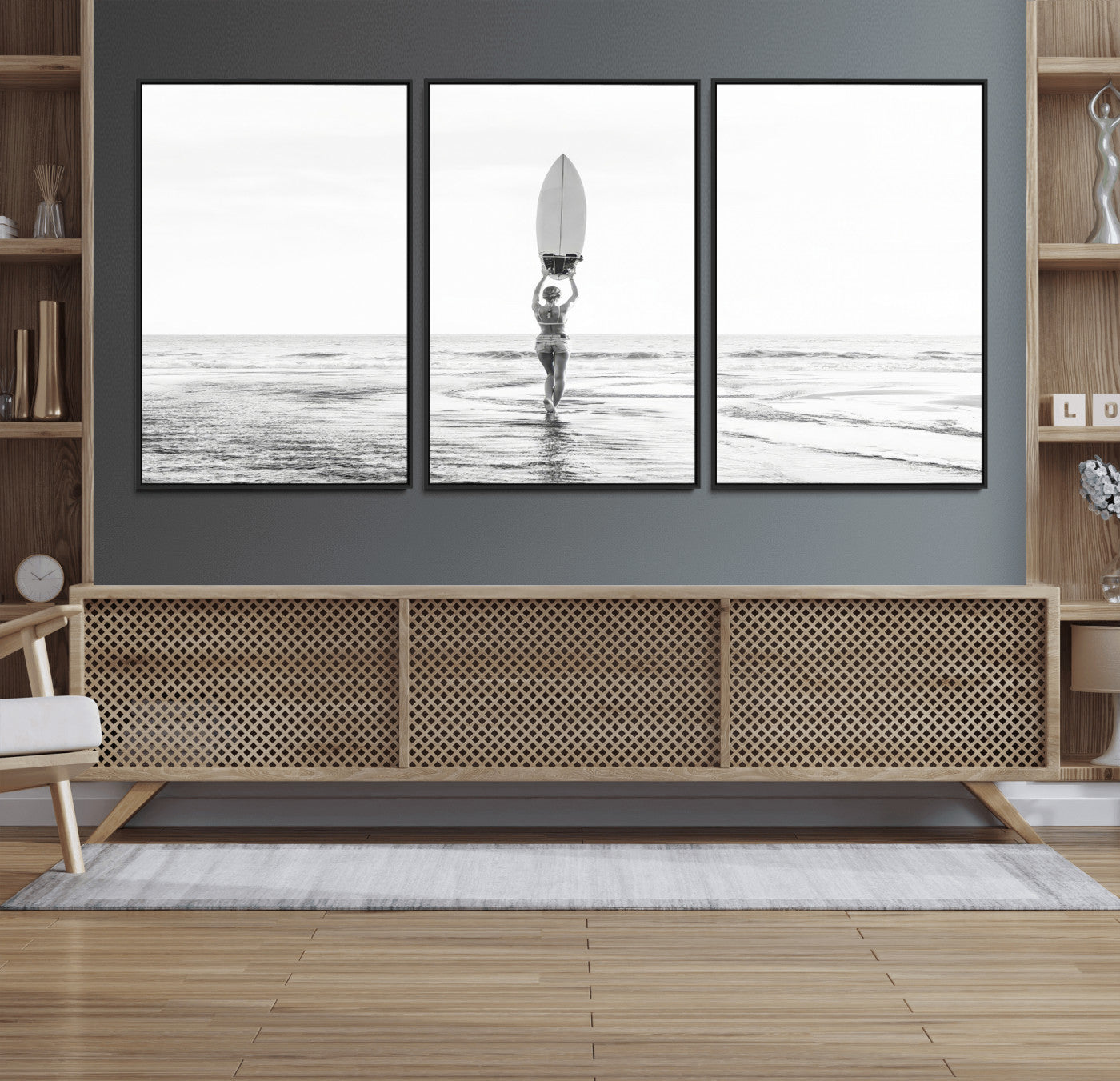 Black and white image of a female surfer holding a surfboard above her head while walking toward the ocean, creating a minimalist and bold coastal aesthetic.
