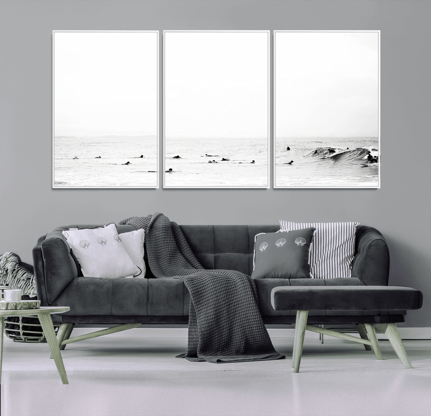 A group of surfers floating in the ocean, waiting for waves under a vast, moody sky, captured in black and white.