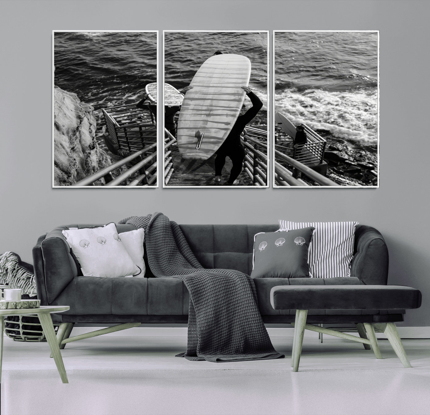 Black and white photo of surfers carrying boards down a rugged cliffside stairway, capturing a bold and adventurous coastal scene.