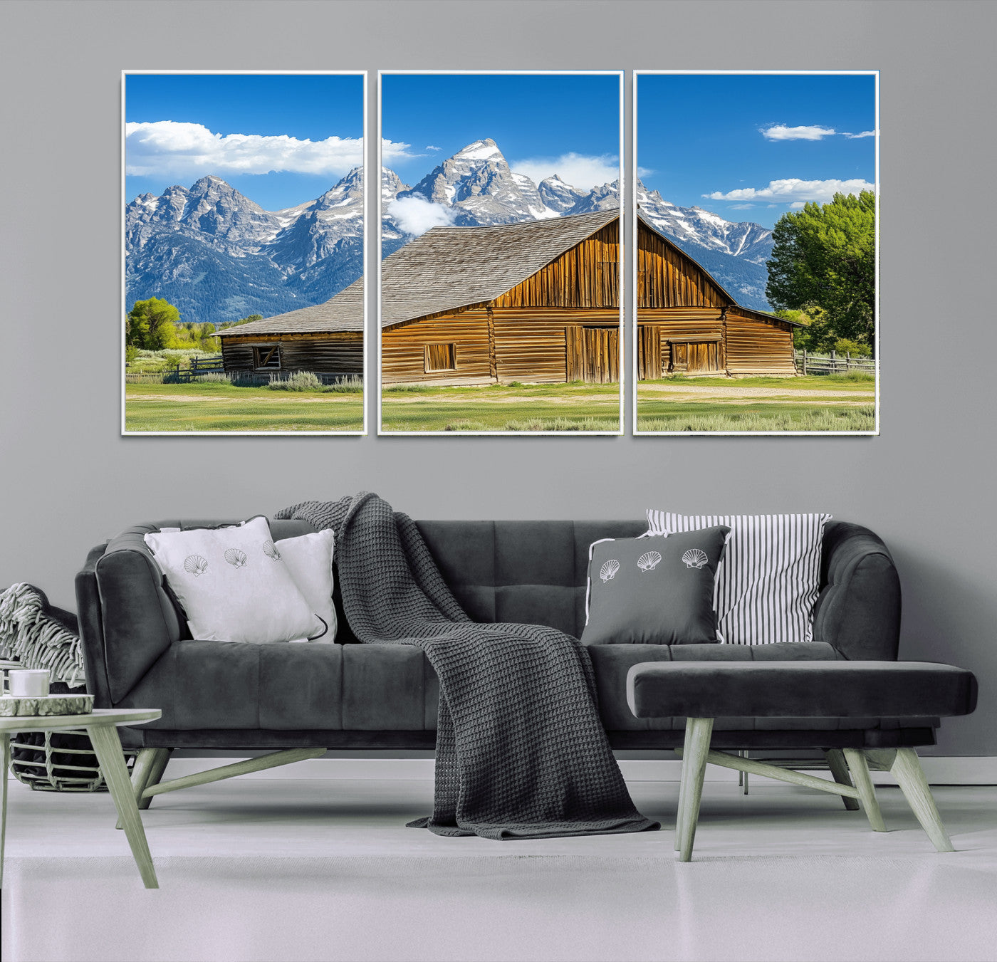 A rustic wooden barn sits in front of towering mountain peaks under a clear blue sky, perfect for farmhouse or cabin style interiors.