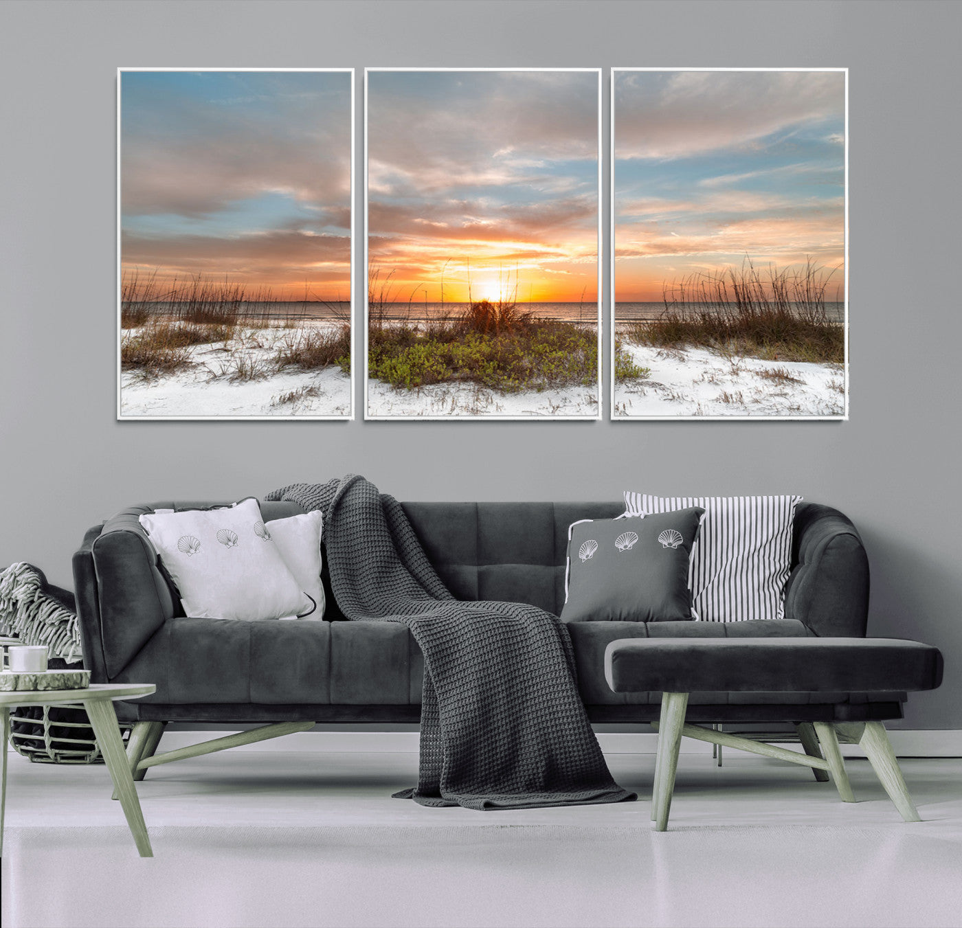 A tranquil beach scene featuring golden sunset hues over the water, with grasses in the foreground and a peaceful, serene atmosphere.