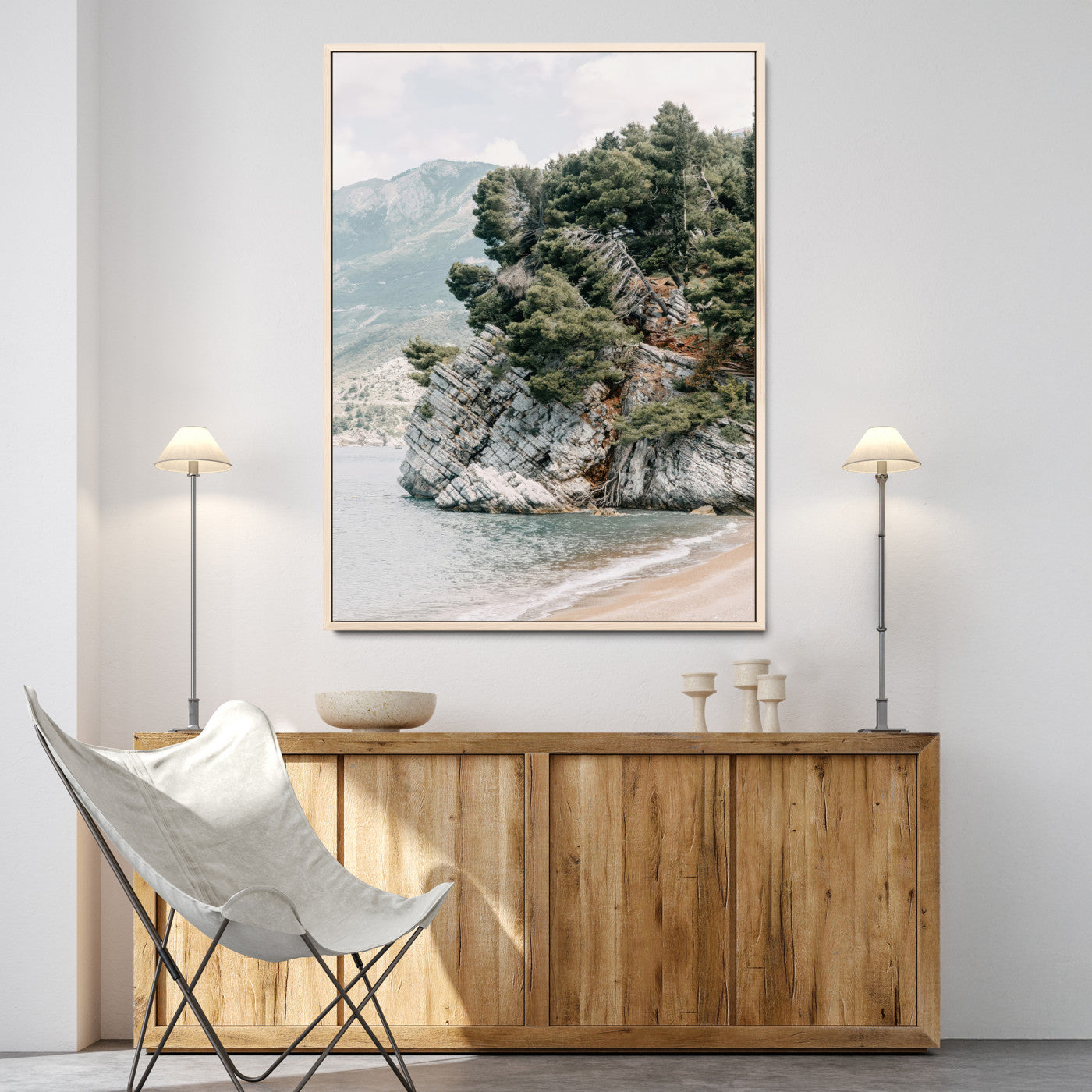Framed photo of a rocky coastal cliff with dense greenery and calm shoreline, ideal for rustic coastal or earthy-toned home decor.