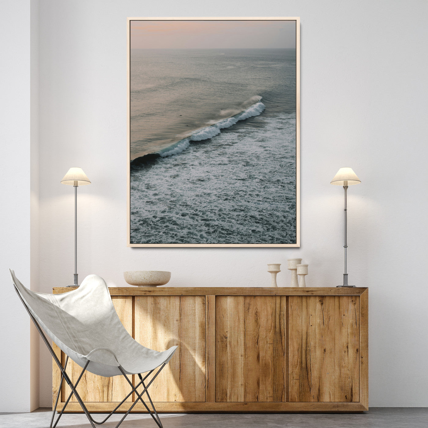 Aerial view of ocean waves rolling towards the shore under a soft sunset sky, creating a peaceful and minimalist coastal scene.
