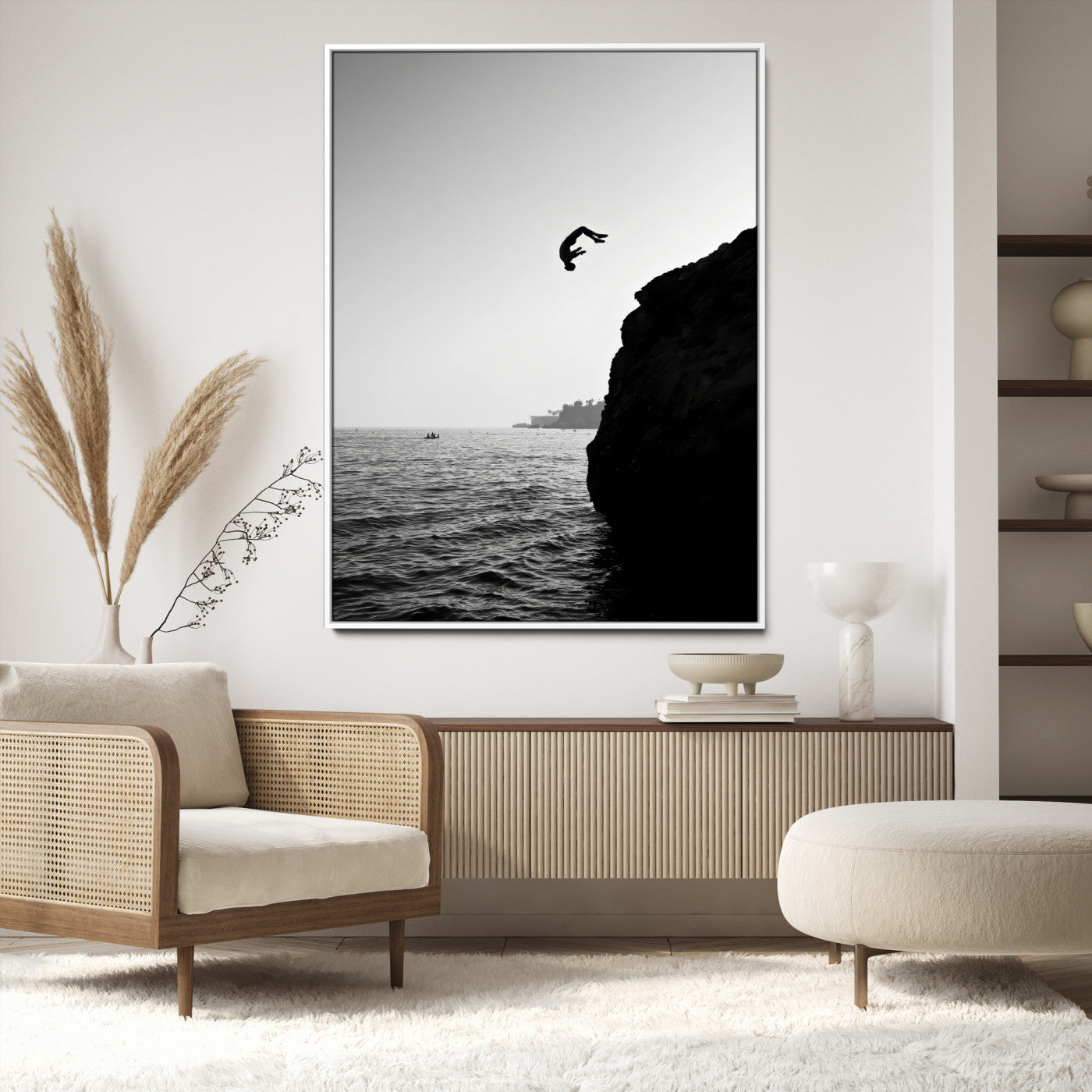 Silhouette of a person mid-air during a cliff jump over the ocean, captured in black and white for minimalist adventure decor.