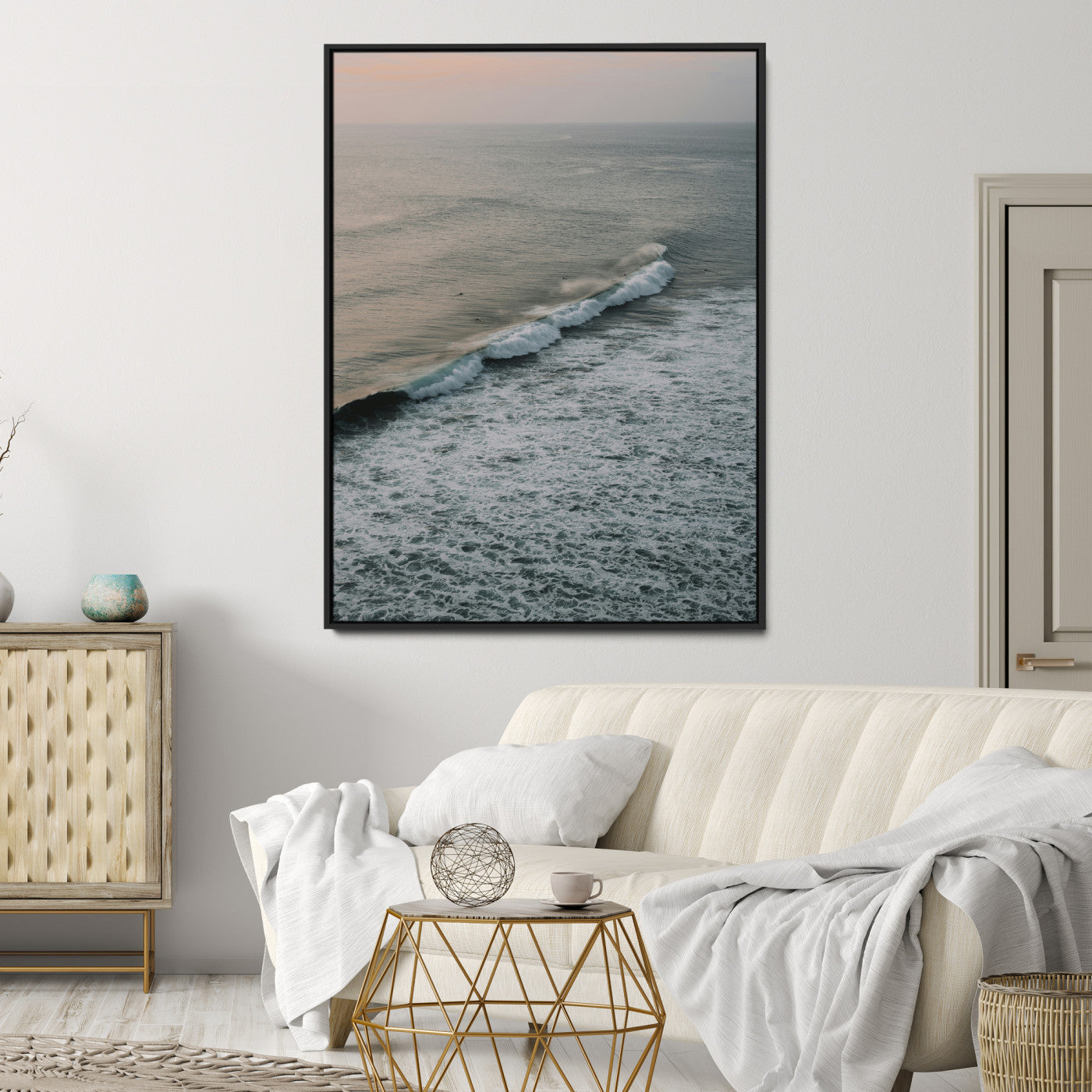 Aerial view of ocean waves rolling towards the shore under a soft sunset sky, creating a peaceful and minimalist coastal scene.