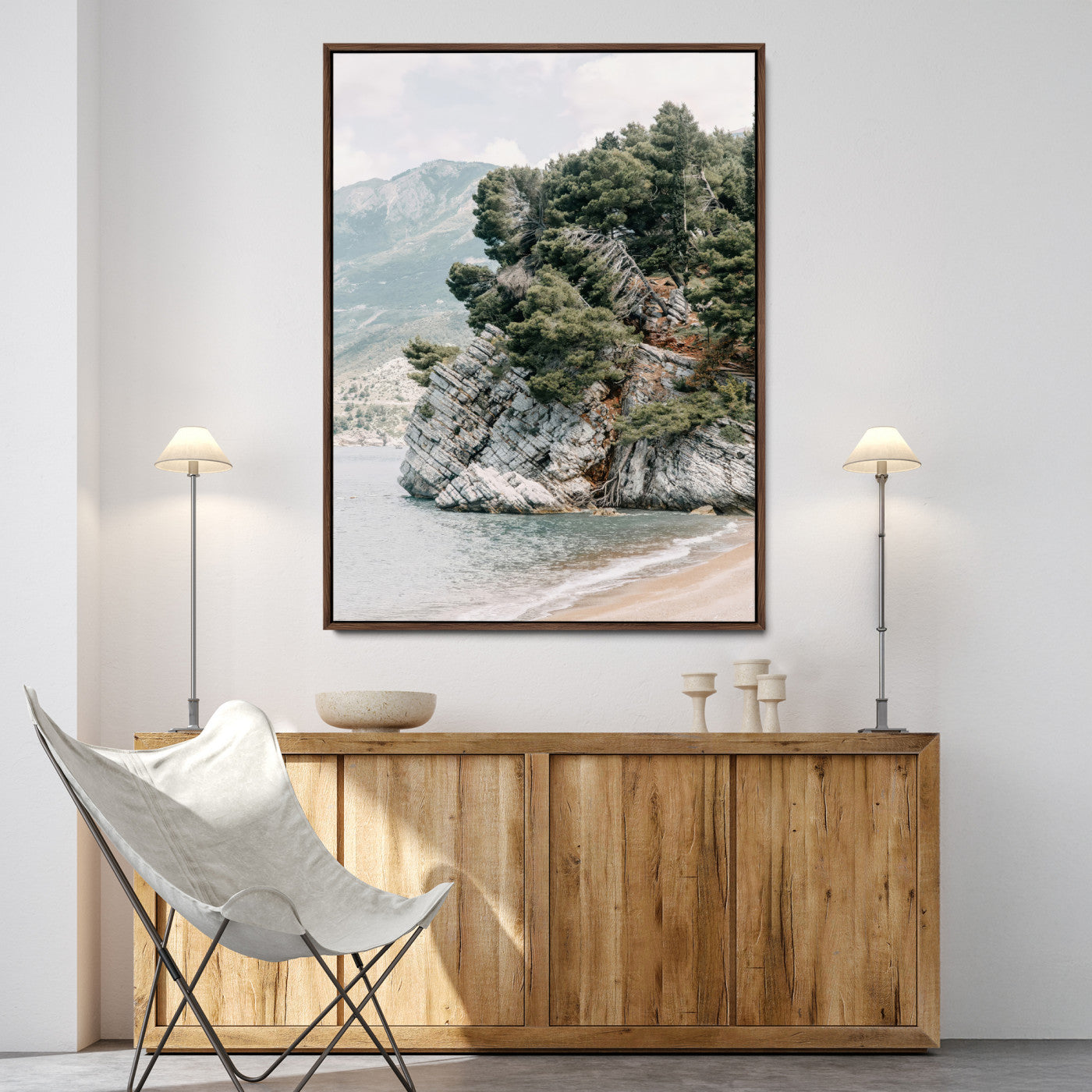 Framed photo of a rocky coastal cliff with dense greenery and calm shoreline, ideal for rustic coastal or earthy-toned home decor.