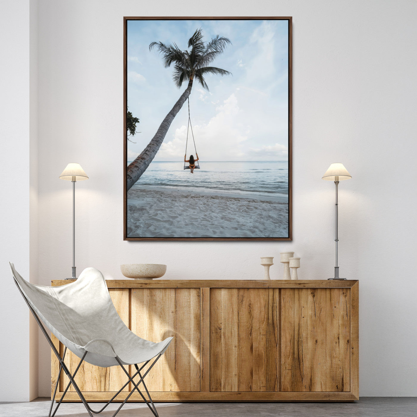 Wall art of a girl on a swing hanging from a palm tree over calm ocean waters, perfect for tropical or minimalist coastal decor.