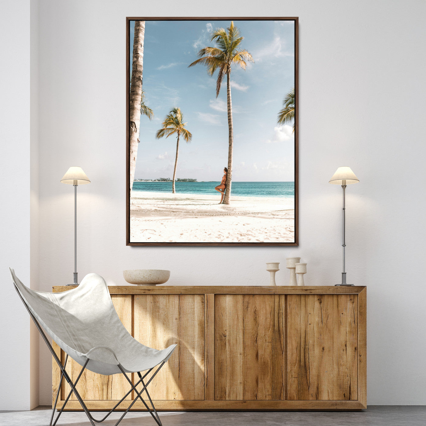 Person leaning on a palm tree at a tropical beach with white sand and turquoise water, perfect for coastal or beach-themed home decor.