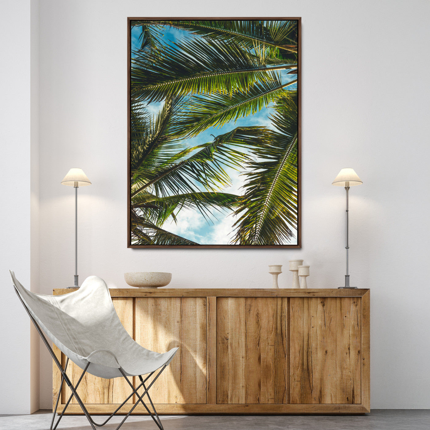 Looking up at lush green palm leaves against a bright blue sky, creating a tropical and relaxing coastal aesthetic.