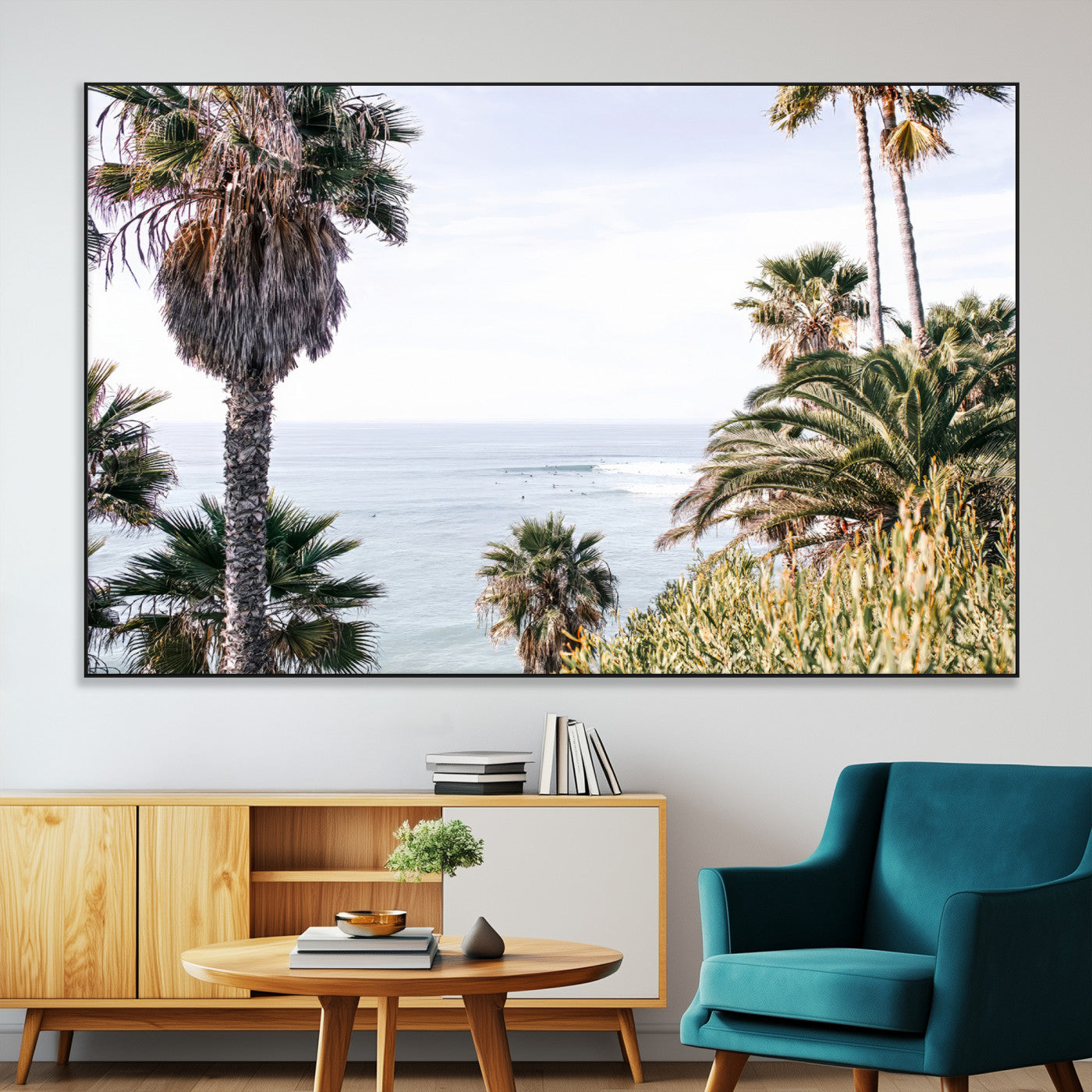 Scenic coastal view with tall palm trees overlooking a calm ocean, soft blue waves, and surfers in the distance, creating a peaceful tropical vibe.