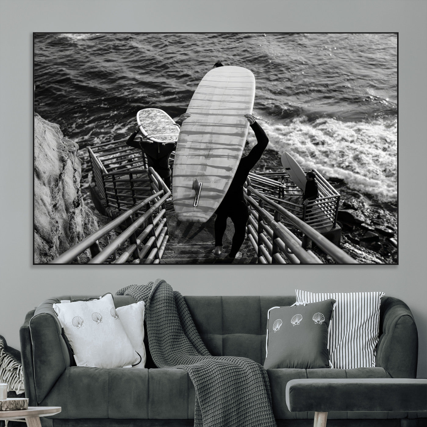Black and white photo of surfers carrying boards down a rugged cliffside stairway, capturing a bold and adventurous coastal scene.